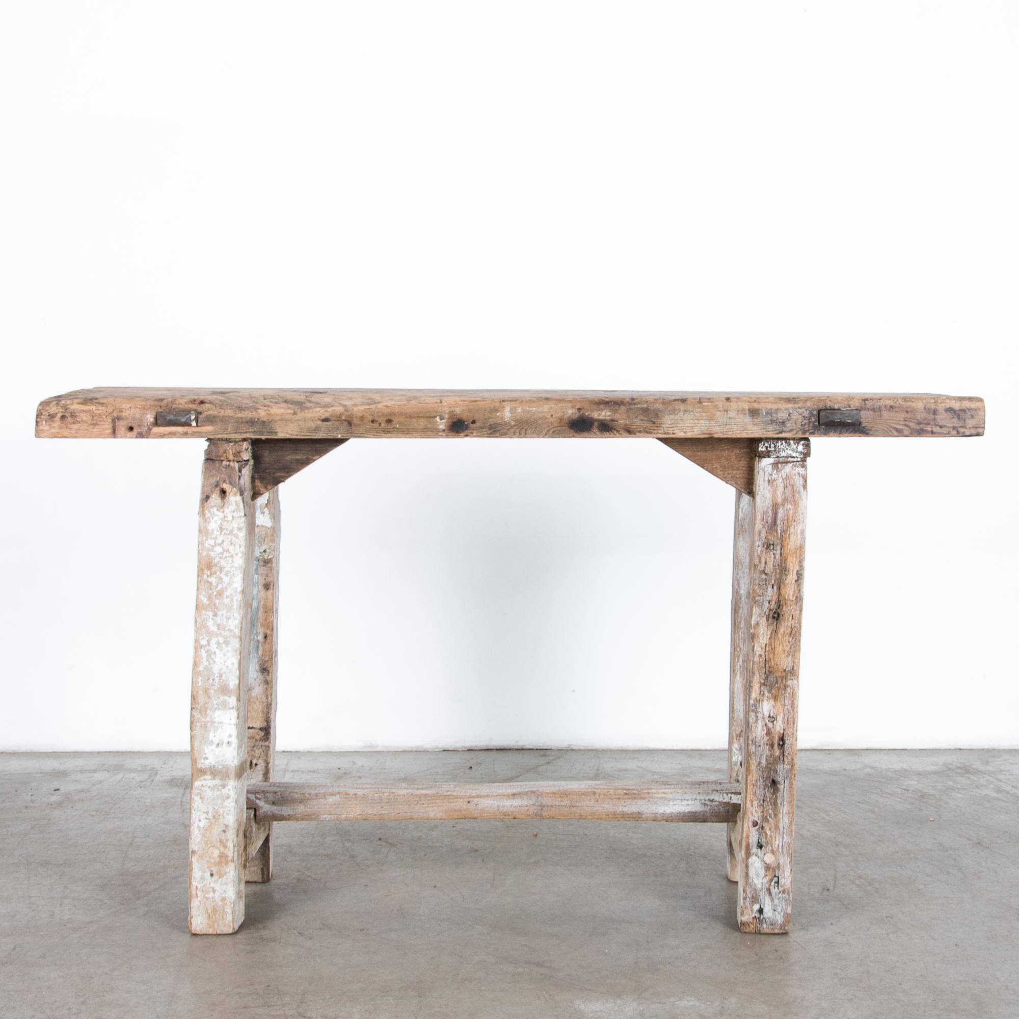 A rustic table from Belgium, circa 1900. Reinforced for heavy duty work angled braces and iron bars echo stability with a visual effect. With textured marks from years of use, this antique furniture piece has a striking effect, with natural tones
