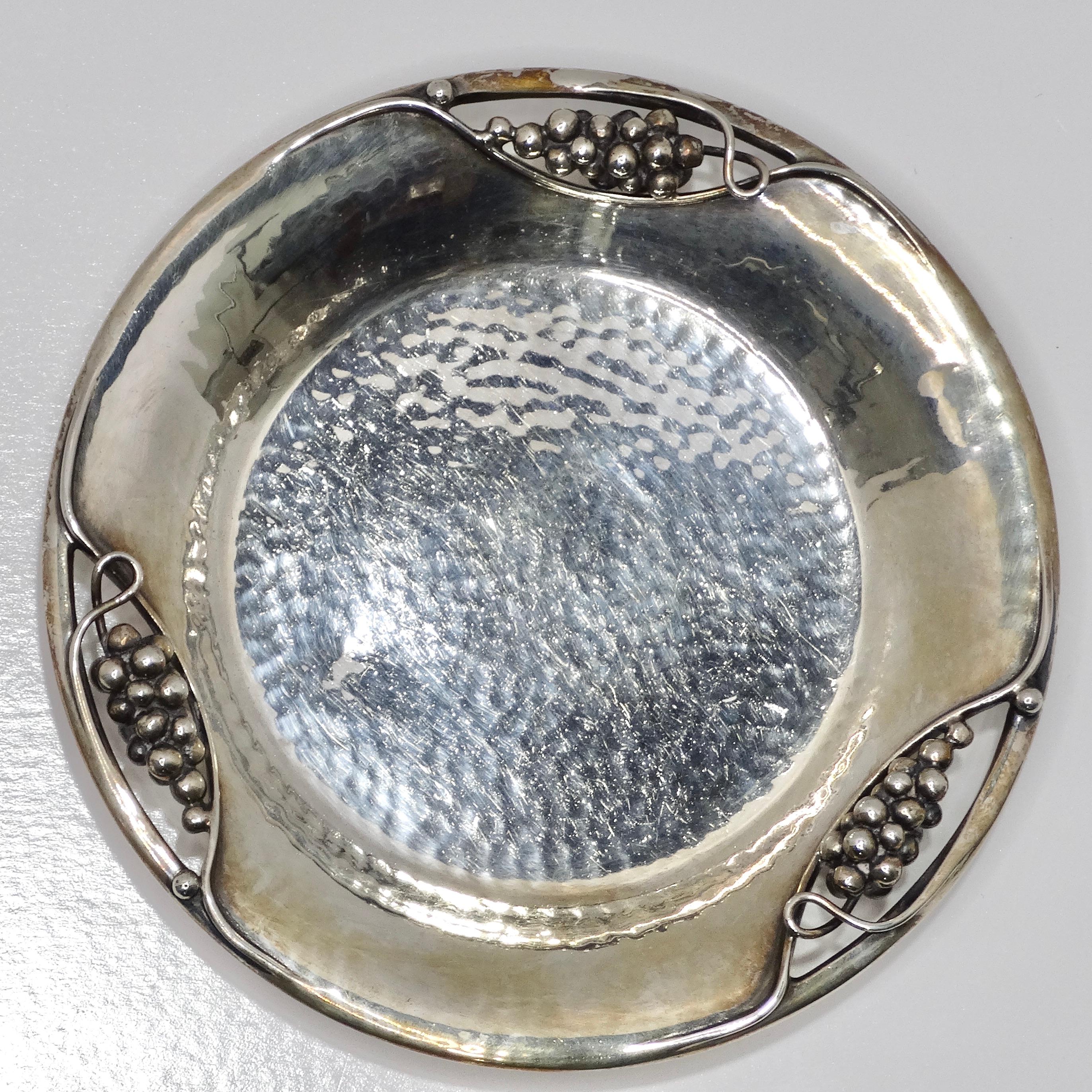 Wir stellen den Antique Pure Silver Grape Motif Plate vor, ein fesselndes Stück, das zeitlose Eleganz und Luxus ausstrahlt.

Dieser Teller aus reinem Silber, der Anfang 1900 hergestellt wurde, zeigt exquisite Traubenmotive, die fein an den Seiten