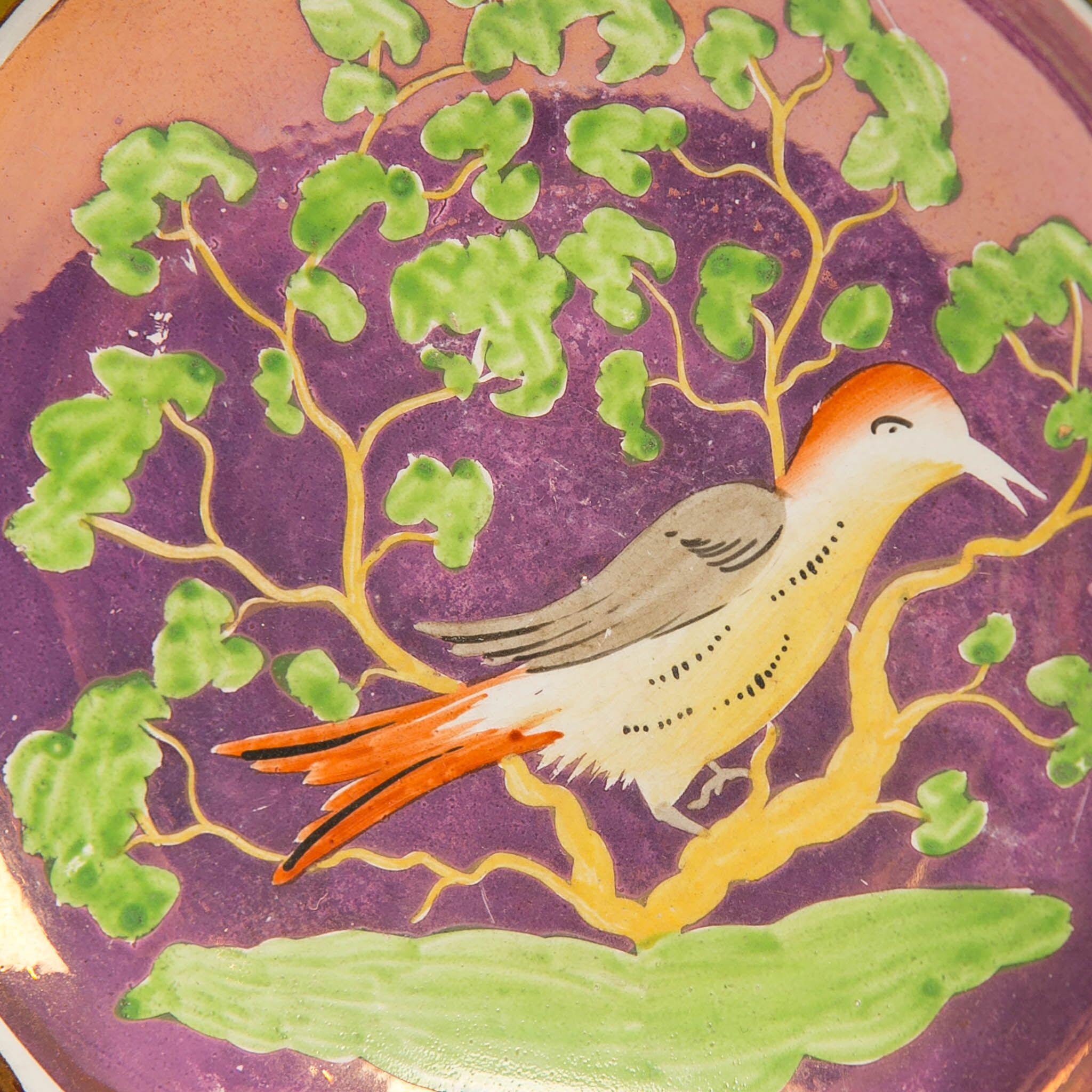 We are pleased to offer this very special lustreware cup and saucer made in England, circa 1830. The cup and saucer both show a hand painted songbird perched in a tree with green leaves and grass on a purple ground. The colors purple and green are