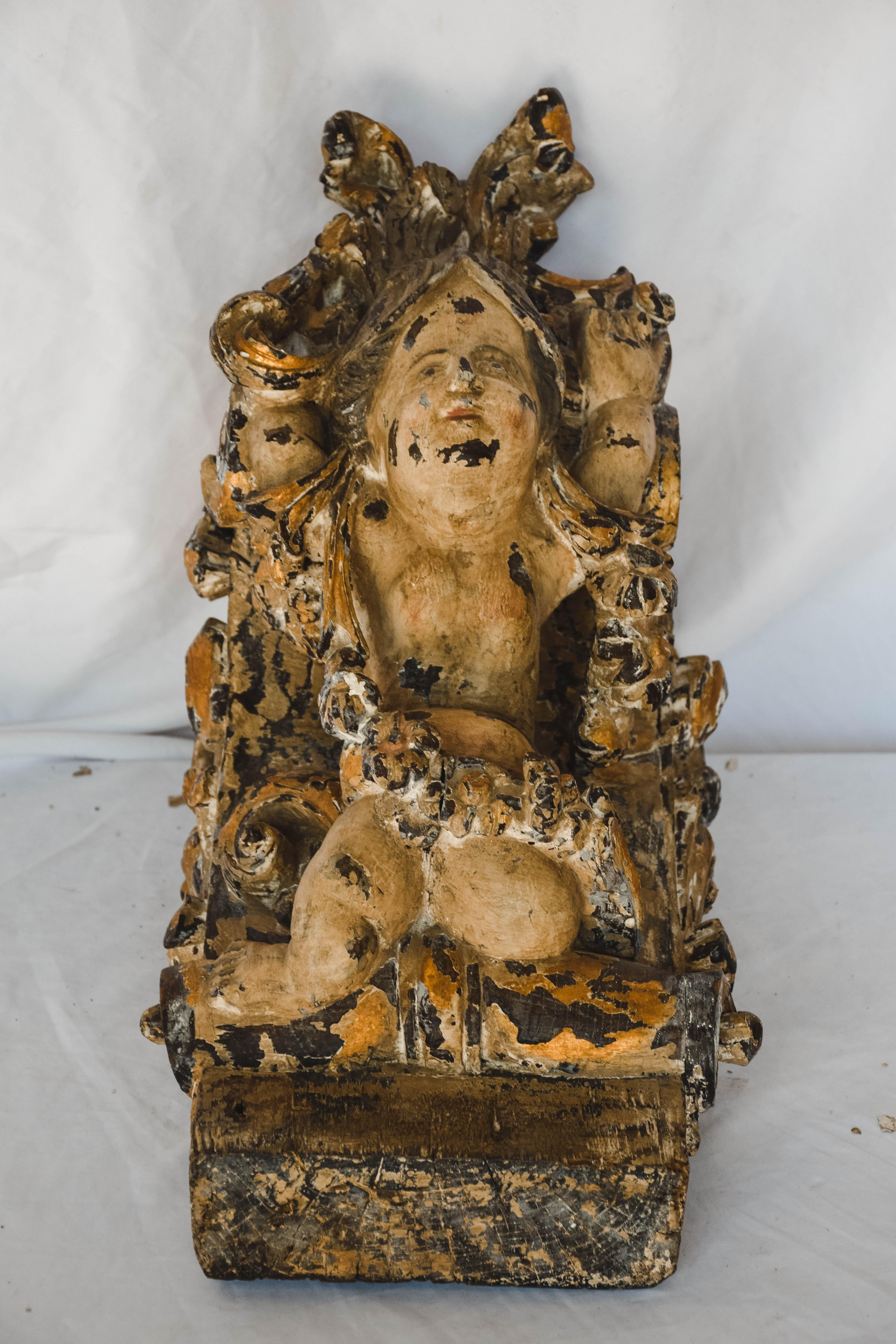 Wood carved and painted Putti from Portugal. Wood is intricately carved and the putti has a sweet smiling face that shows through with a natural patina of age. This piece could be used as a corbel, wall décor, or a shelf.