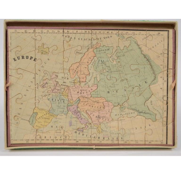 Puzzle éducatif en carton coloré composé de trois dossiers représentant la carte du monde, l'Europe et la France. La carte du monde, en plus de la carte territoriale des continents, représente les phases de la Lune et le mouvement des planètes.