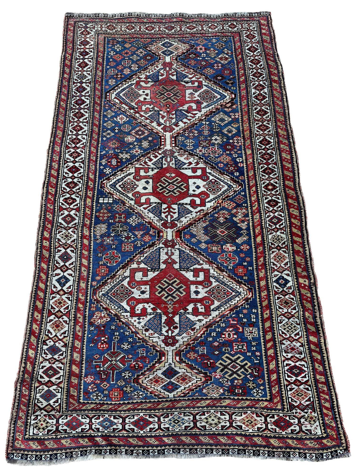 Ein wunderschöner antiker Stammesteppich, gewebt vom Nomadenstamm der Gaschgai um 1900. Das Design zeigt drei geometrische Medaillons auf einem indigoblauen Feld, umgeben von einer elfenbeinfarbenen Bordüre. Fein gewebt für einen Tribal-Teppich mit