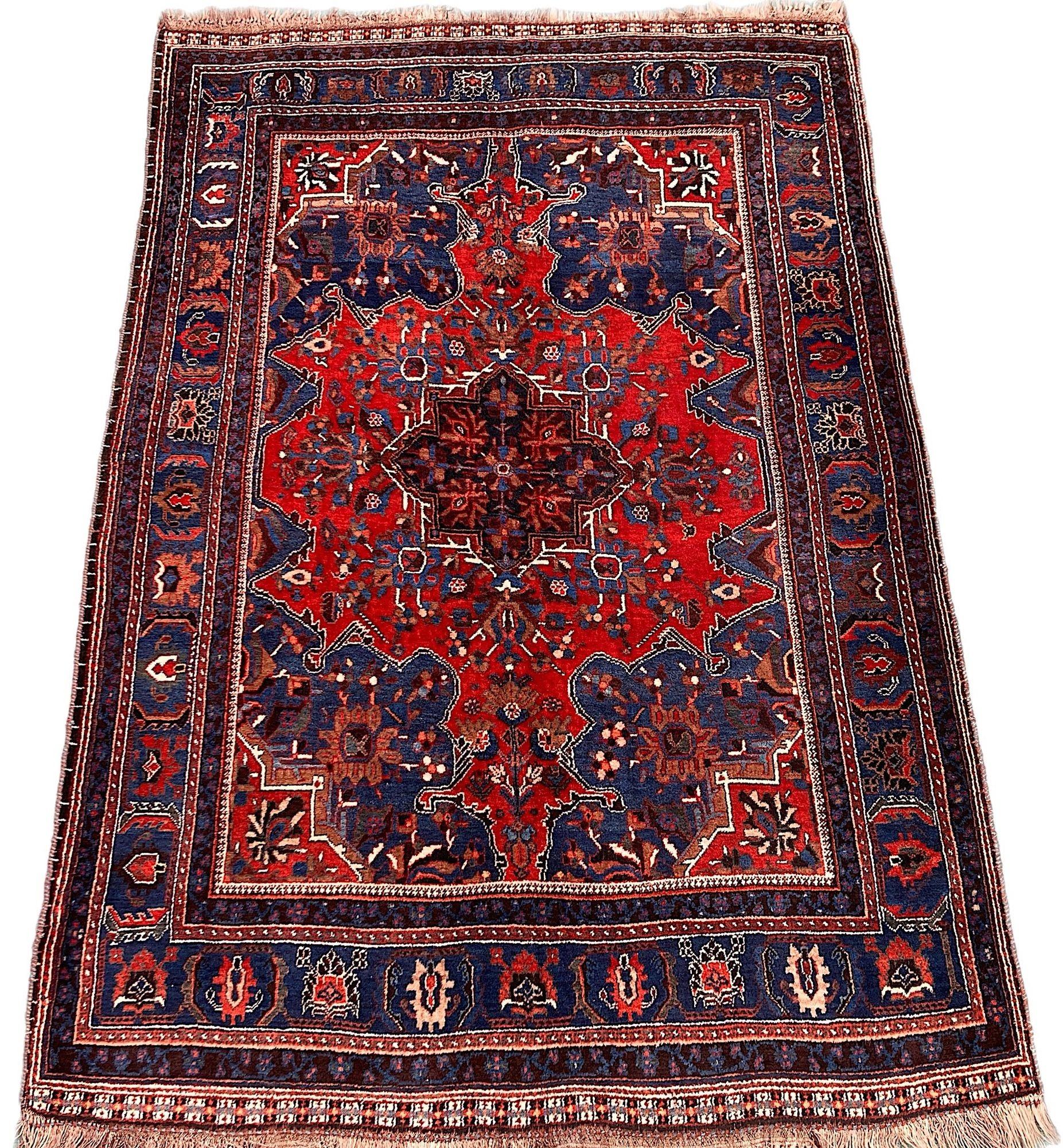 Ein wunderschöner antiker Gaschgai-Teppich, handgewebt von dem gleichnamigen Nomadenstamm um 1910. Der Teppich zeichnet sich durch ein ungewöhnliches kurvenförmiges Muster auf einem reichen Terrakotta-Feld und einer tiefblauen Bordüre aus. Fein