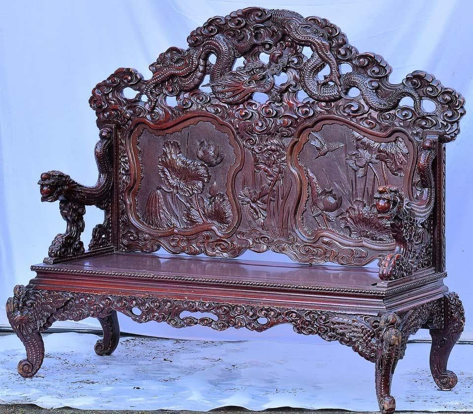 From the late Qing dynasty in China. This exceptionally beautiful love seat bench in elmwood features a hand-carved dragon and floral seat back, sculpted dragon arms and legs. The seat is composed of one long wood plank.

It offers a rich and deep