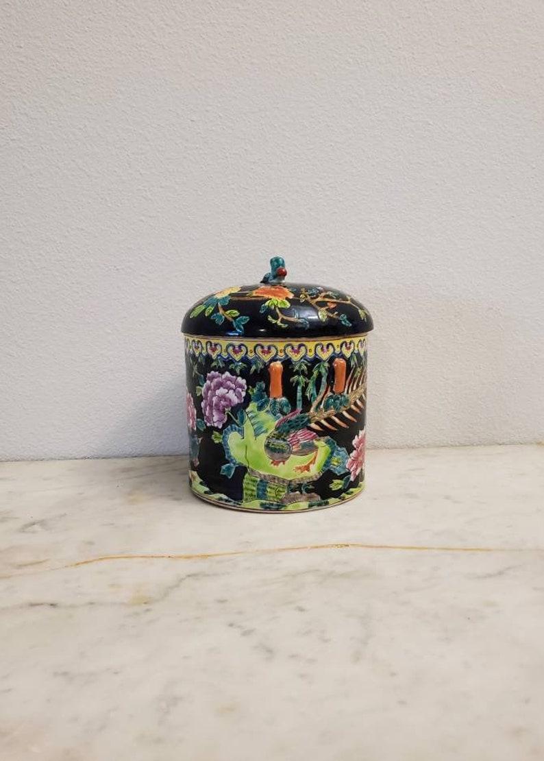 A late Qing Dynasty (1636-1912) porcelain famille noir covered jar with foo dog finial.

China, early 20th century, lidded cylindrical vessel form, having a fitted lid surmounted by foo dog / imperial lion finial, featuring hand painted mythical