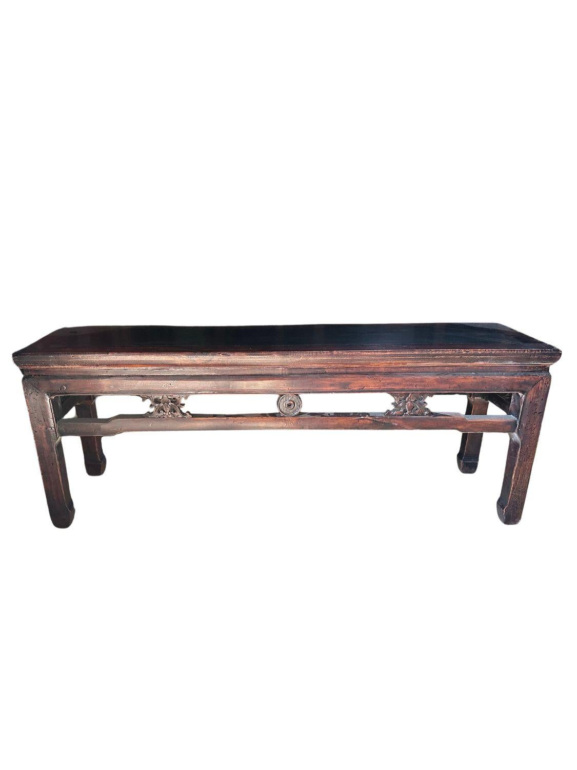 This antique Qing Dynasty dark elm wood bench, dating back to circa 1880, is a stunning example of traditional Chinese craftsmanship. The bench features a rectangular top with a smooth, dark finish, supported by four sturdy legs. The legs are
