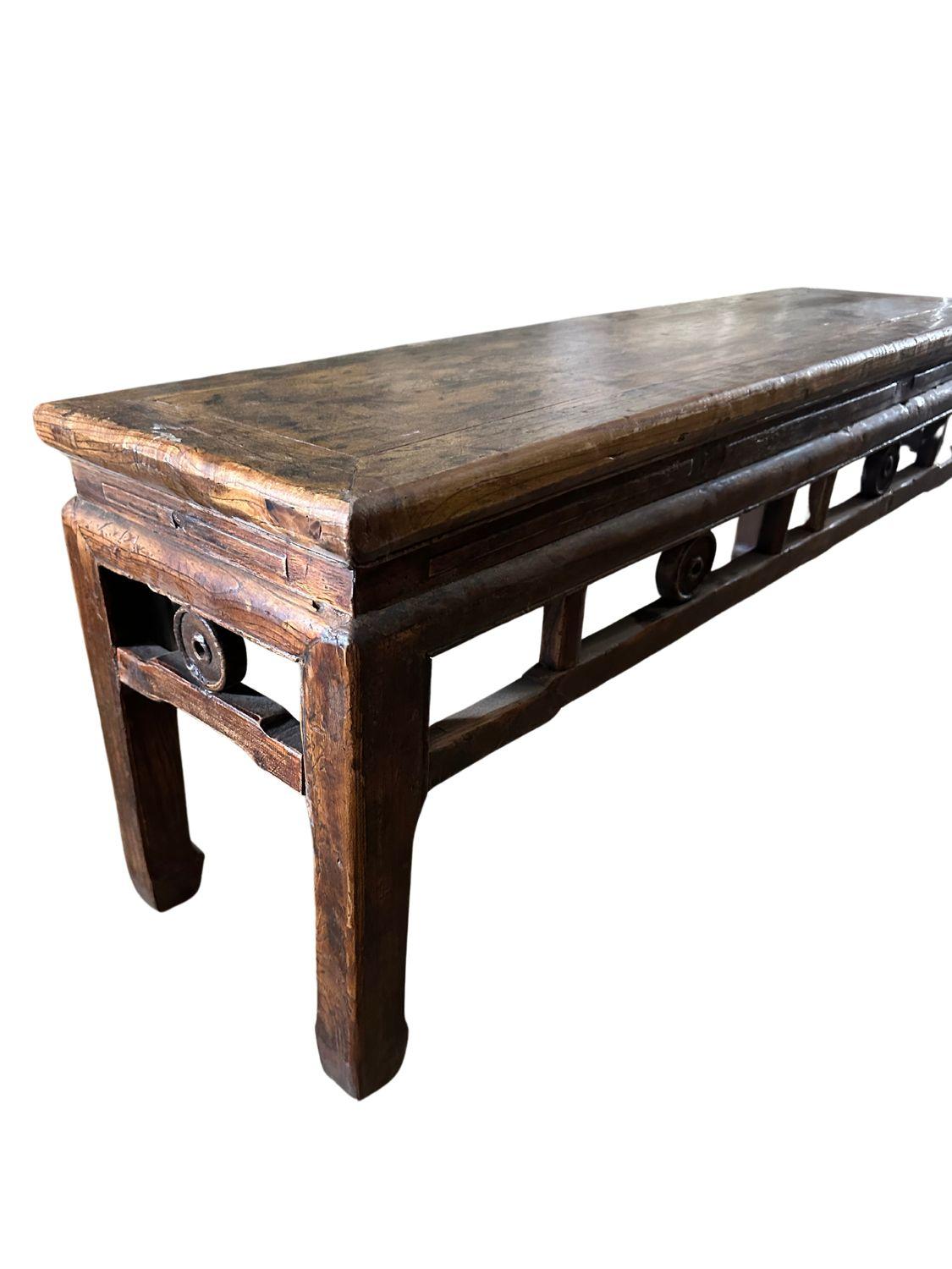 This antique Qing Dynasty elm wood table, dating back to circa 1880, is a stunning example of traditional Chinese craftsmanship. The table features a rich, warm patina that highlights the natural beauty of the elm wood. Its rectangular top is