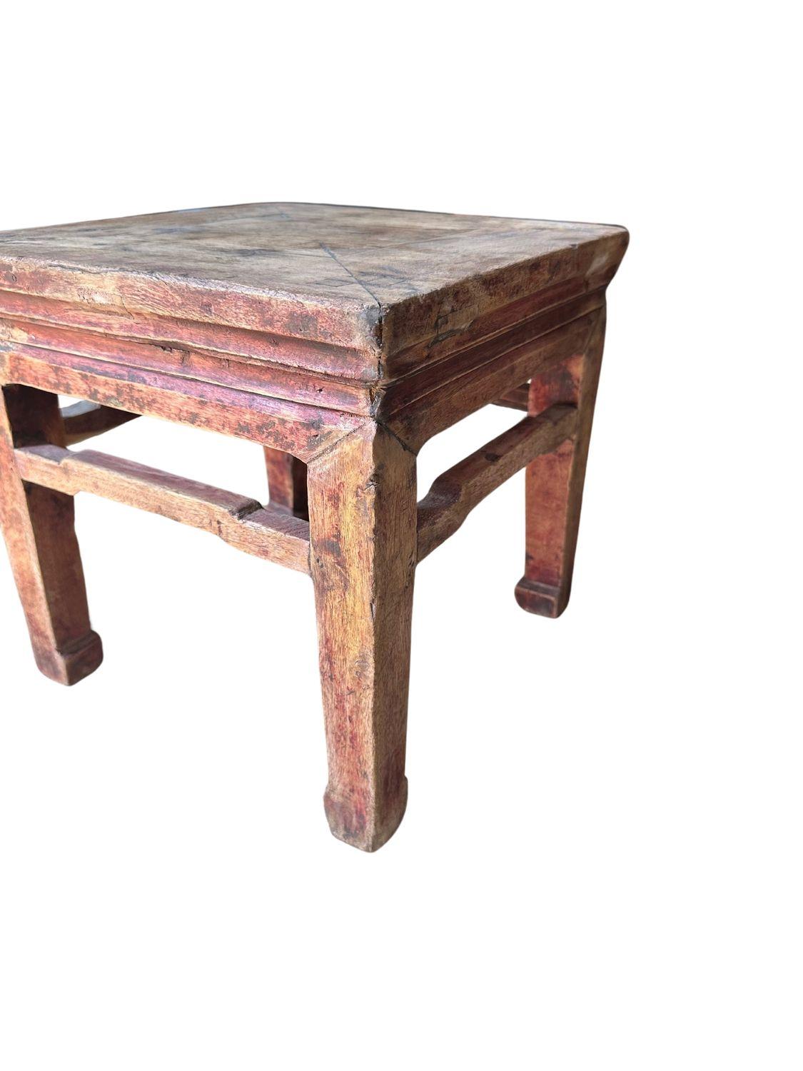 This antique Qing Dynasty elm stool, dating back to circa 1890, is a piece of traditional Chinese craftsmanship. Crafted from premium elm wood, this stool radiates a rich patina that tells a story of centuries past. The stool features a square top