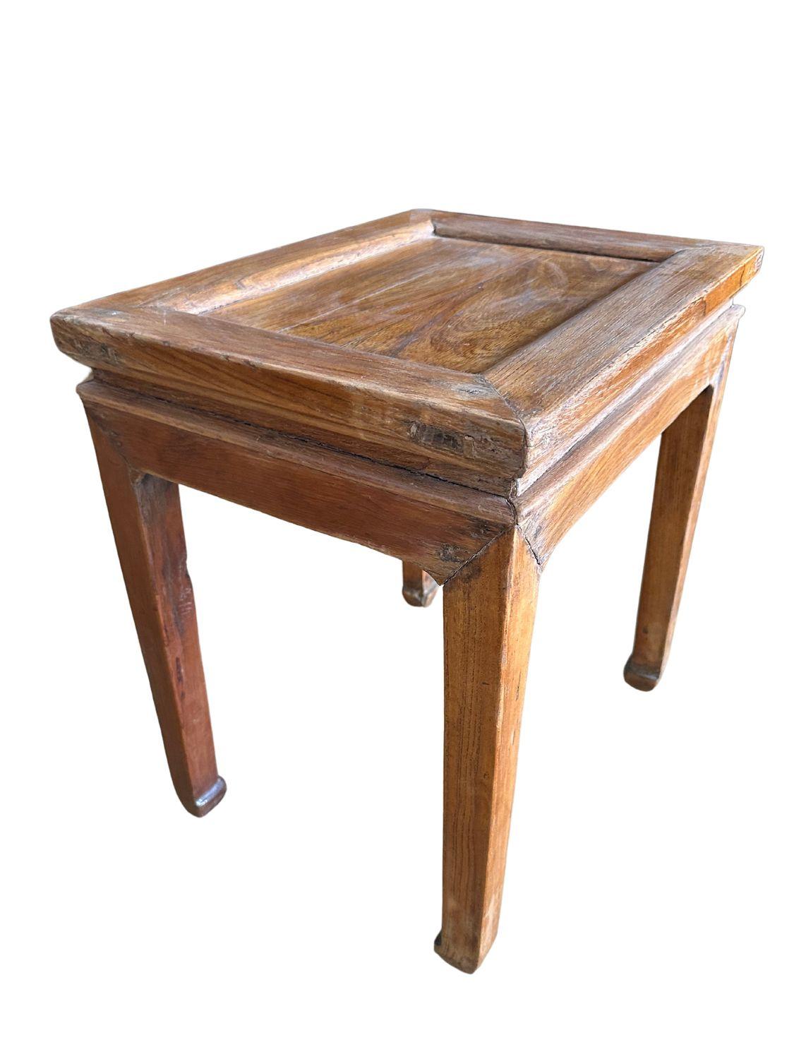 This antique Qing Dynasty light elm stool, dating back to circa 1910, is a captivating piece of traditional Chinese craftsmanship. Crafted from solid light elm wood, it features a warm, natural finish that highlights the wood's beautiful grain
