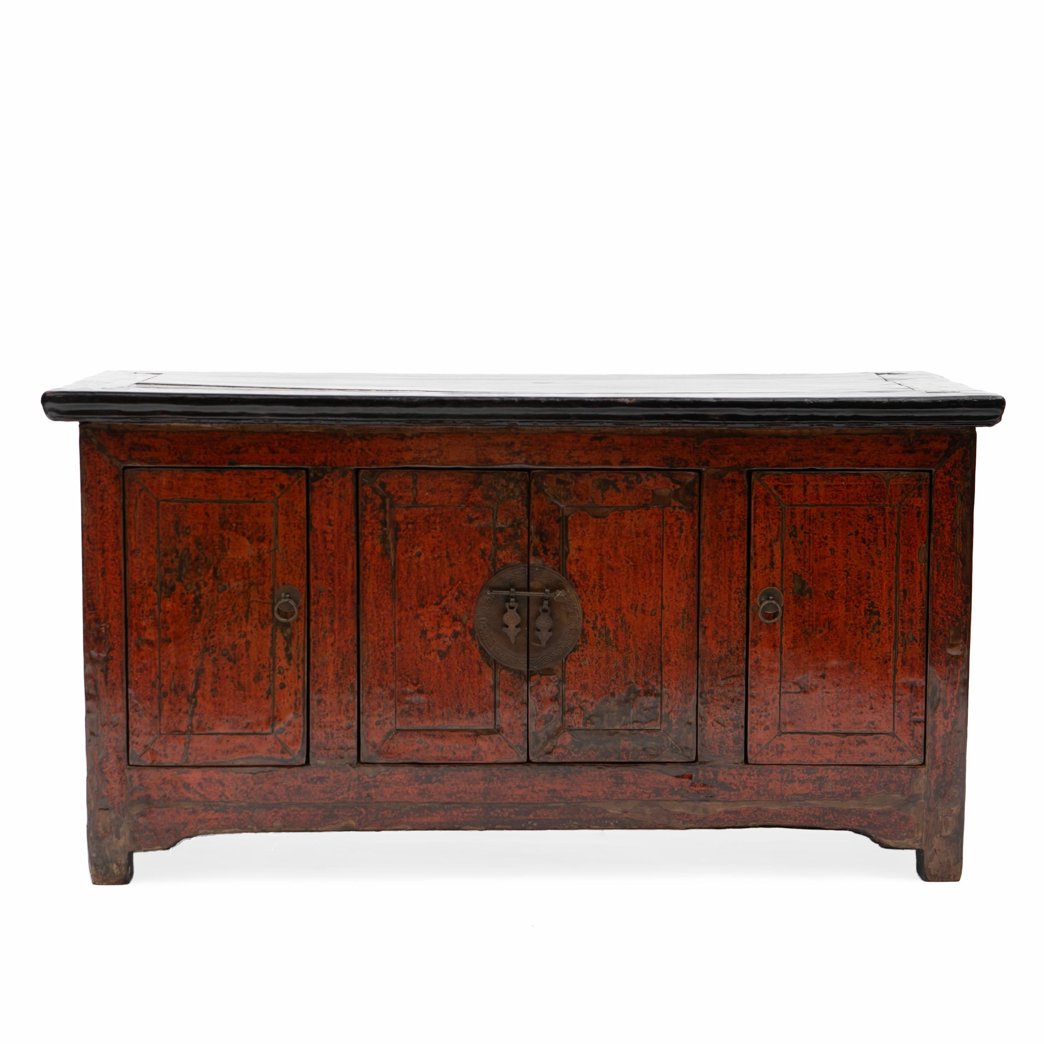 Low sideboard (kang sideboard) from the Qing period in elm wood with original red lacquer on the front, black lacquer on the sides.
Front with double doors in the middle adorned with round metal fittings, flanked by a door on each side.
The
