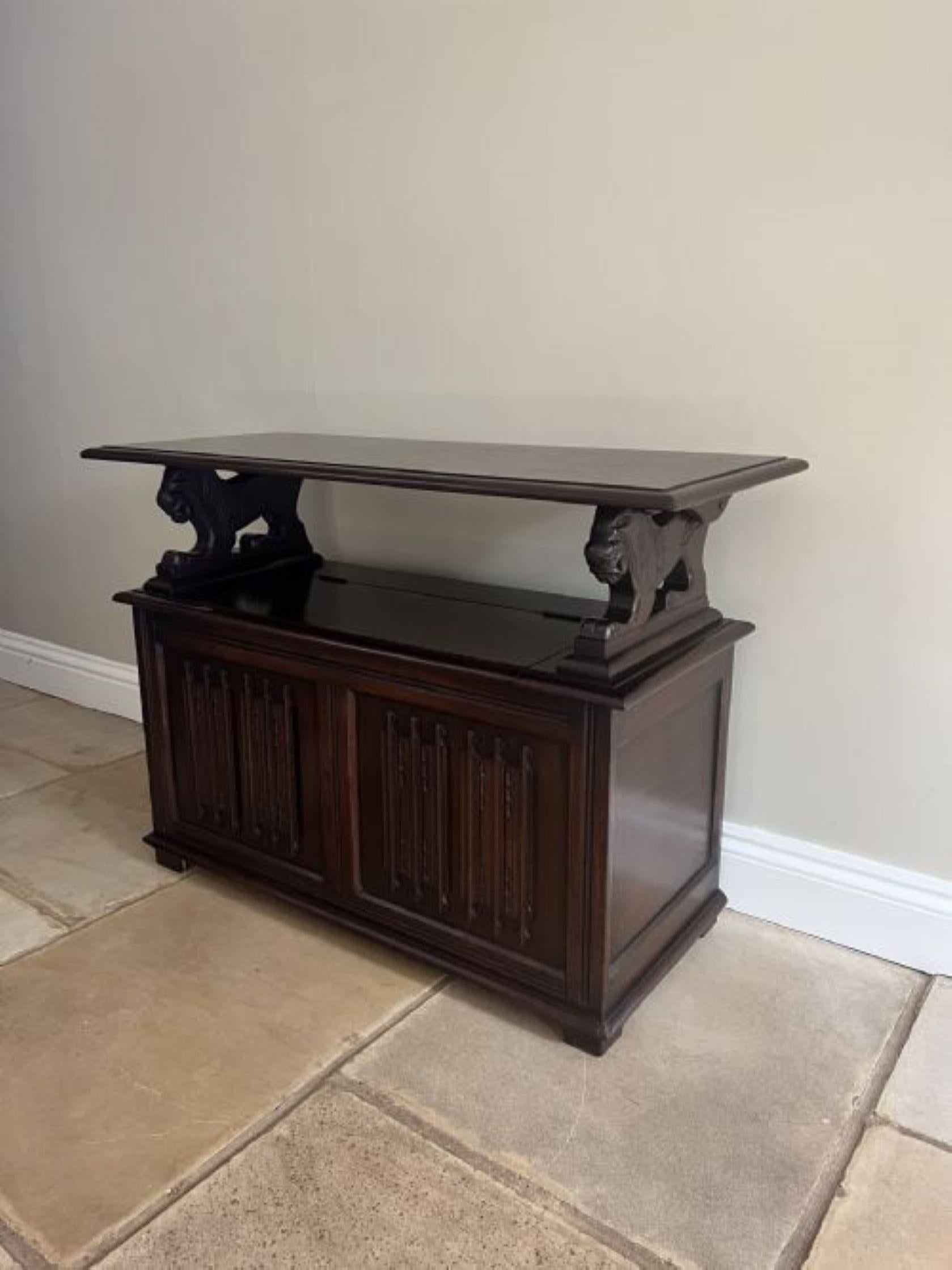 Antique quality carved oak monks bench having a quality carved oak fold over rectangular shape top with a moulded edge, supported by a pair of carved lions above a lining fold carved panelled seat with a lift up lid opening to reveal a storage