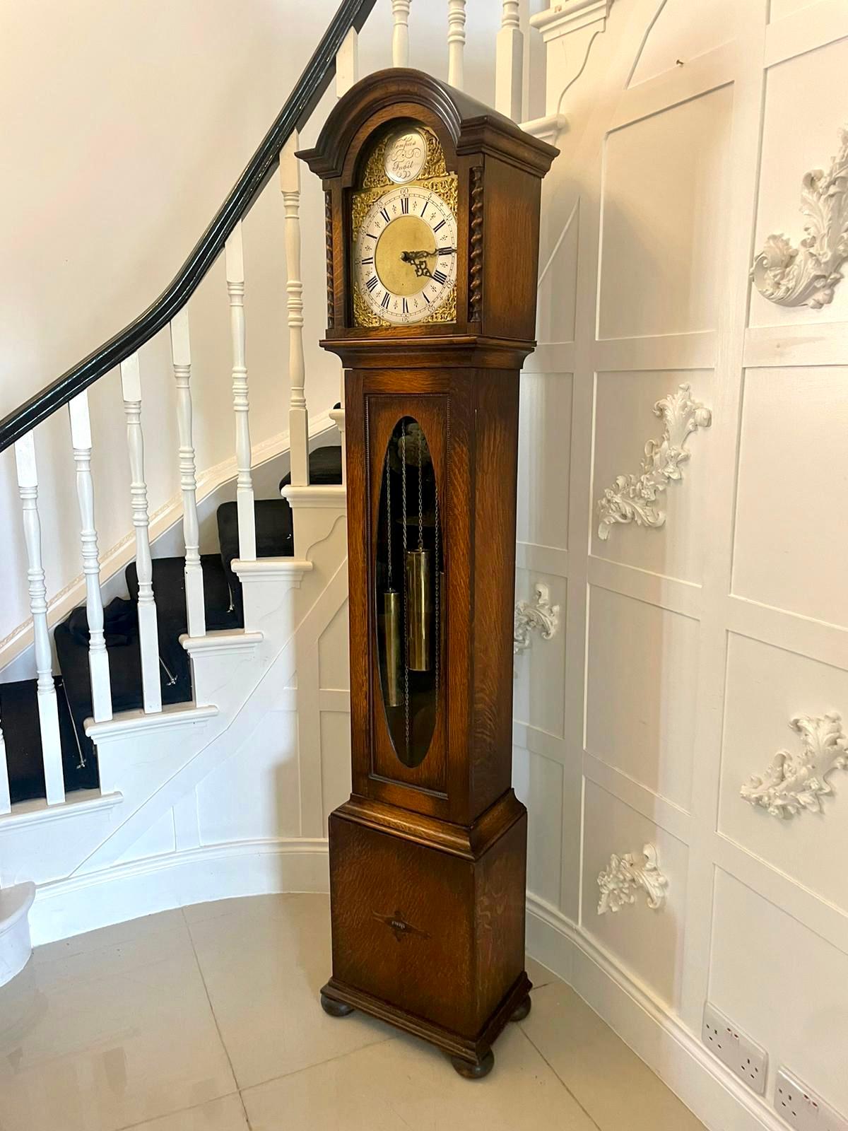 Antique quality oak brass face chiming grandmother clock having a brass arched dial with original hands, 8 day movement chiming every 15 minutes, original 3 brass weights and pendulum, barley twist columns to the sliding hood oval glass panel door