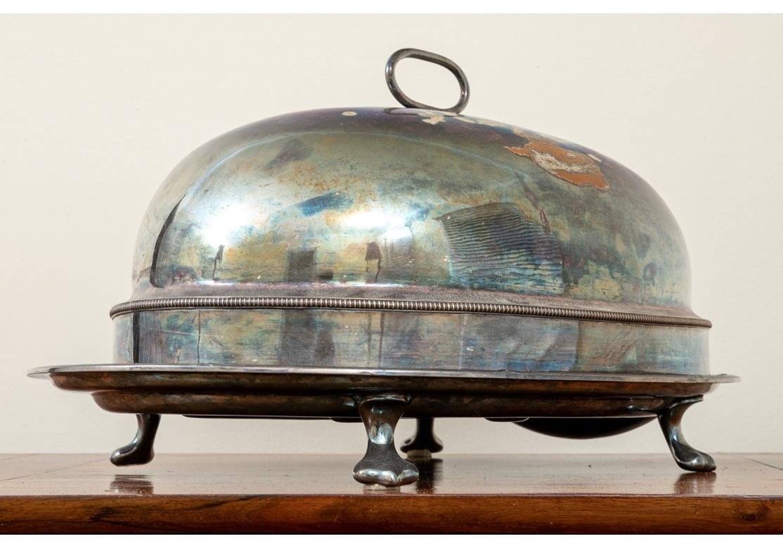 A classic Oval Serving Dome by Elkington. With gadrooned middle band, incised crown motif and top loop handle. Along with an oval paw footed deep meat platter. Dome dimensions are given above. 
dome 15 1/4 x 21