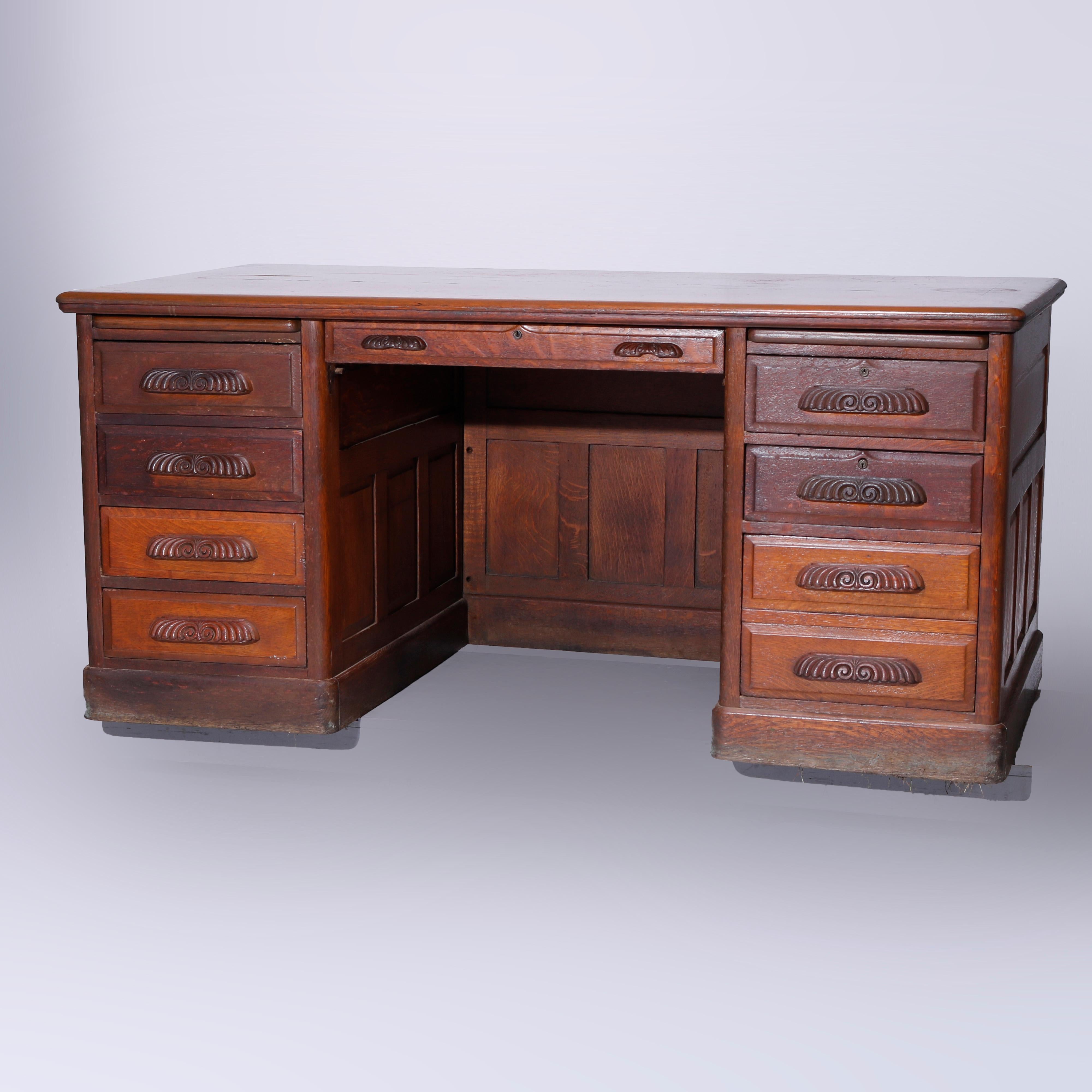 An antique desk offers quarter sawn paneled oak construction in knee hole form with central drawer flanked by pull-out work spaces over drawer towers having Stylized foliate carved pulls, c1900

Measures - 30.5'' H x 66'' W x 36.25'' D.