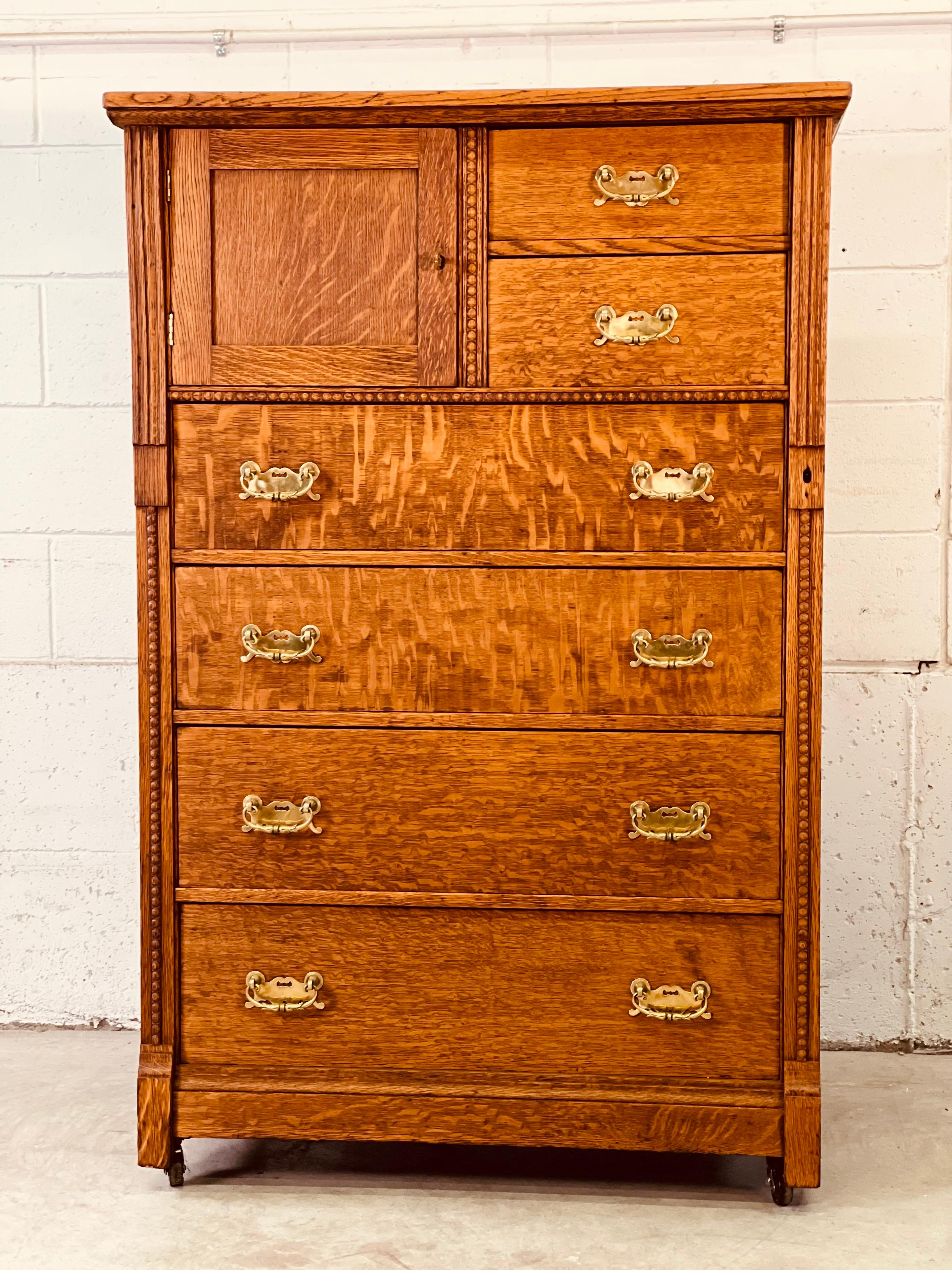 Antique quarter sawn oak wood tall dresser with brass pulls. The dresser has six drawers for storage and a square open area for additional storage. The dresser comes with a brass key that is for two locks. Neither lock is operational. The dresser is