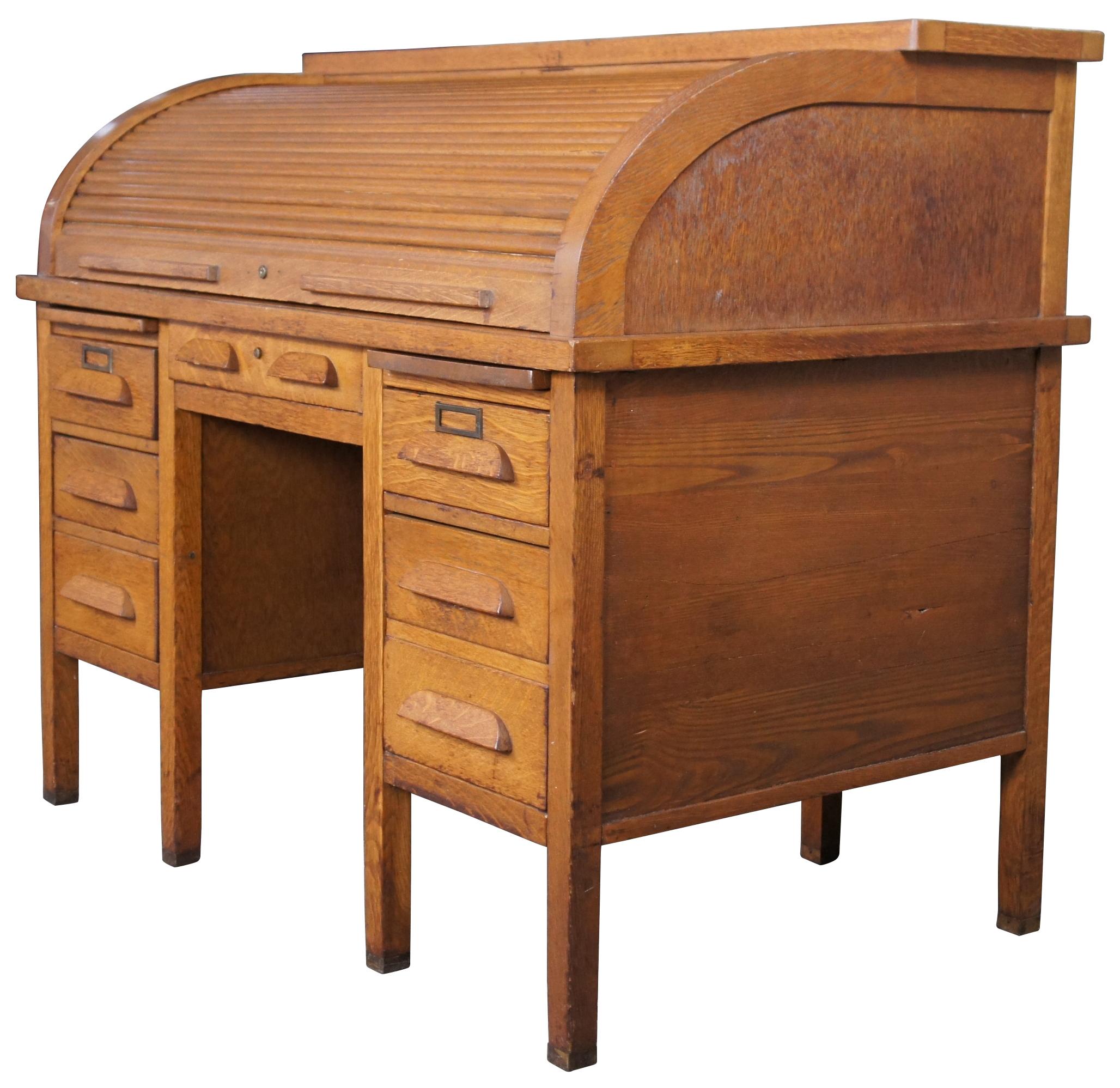 Early 20th century antique quartersawn oak C curve roll top desk. Features rectangular form with large lockable tambour door, six drawers, multiple letter / index / files / and cubbies. Includes brass capped feet. Measure: 44