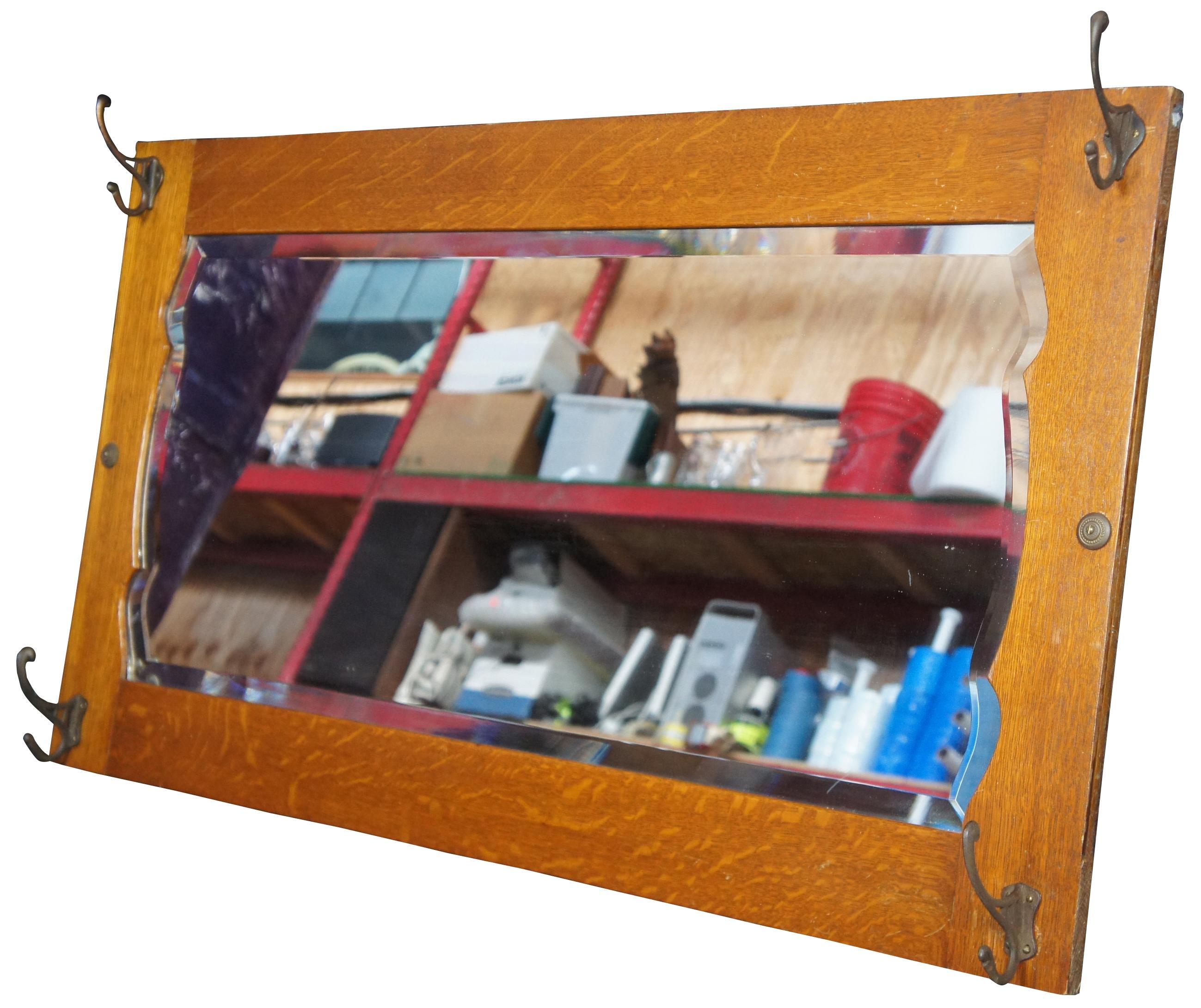 Antique quarter sawn or tiger oak hall mirror or tree with hooks. This coat or hat rack features a beveled mirror with ornate scalloped design against oak paneling and four hooks. Measures: 46