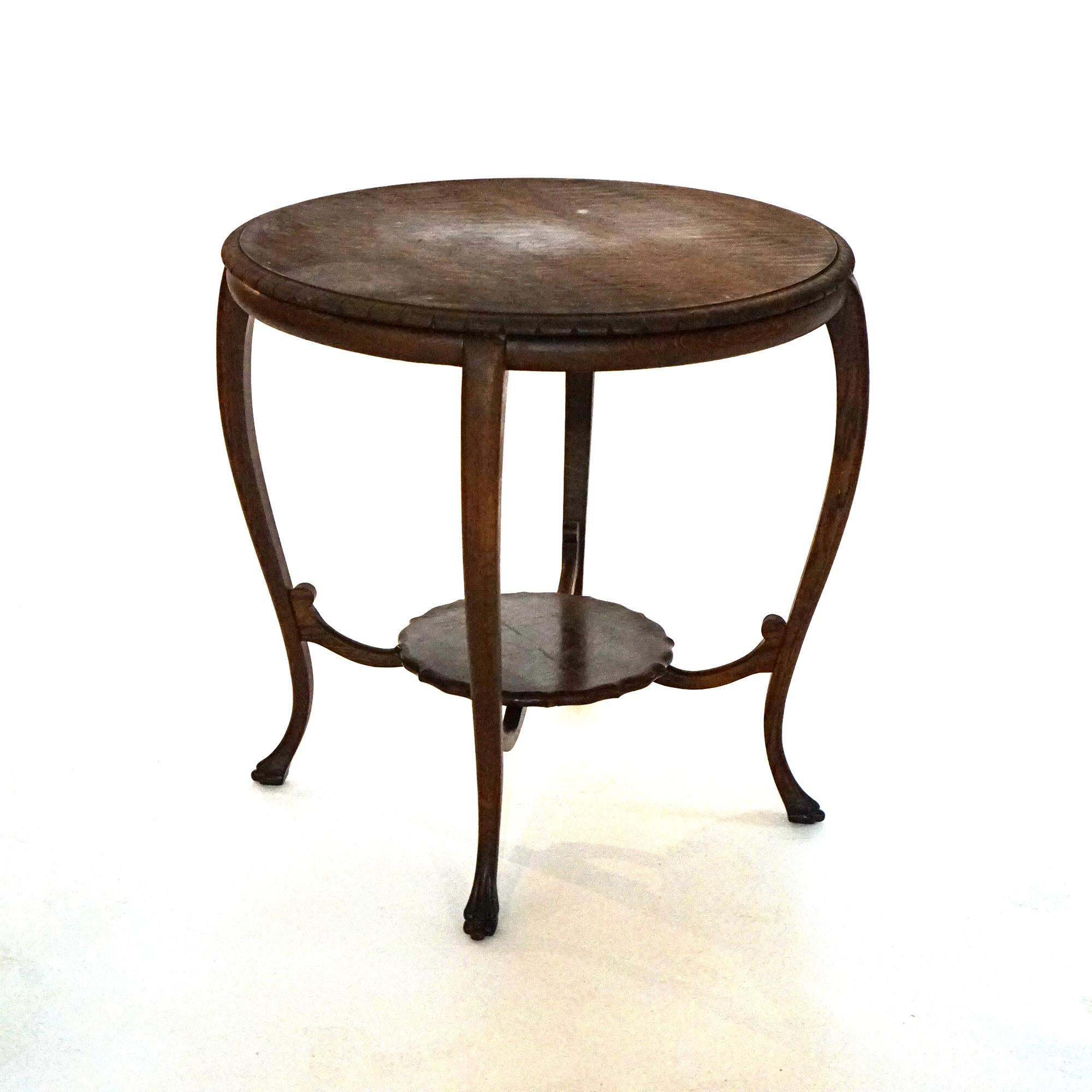 An antique parlor center table offers quarter sawn oak construction with circular top raised on cabriole legs terminating in carved paw feet and having lower scalloped display with scroll form stretchers, c1900

Measures- 29.5'' H x 31.25'' W x