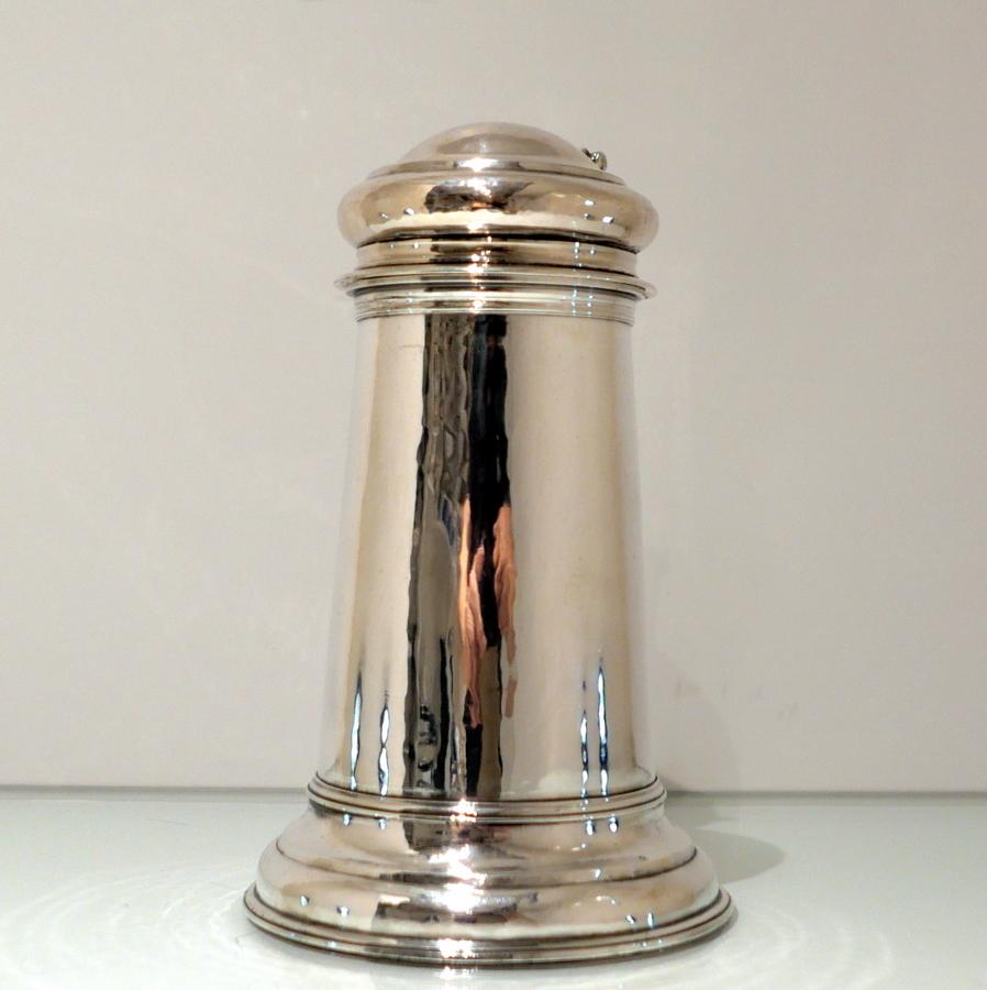 A rare and extremely collectable Britannia silver Queen Anne plain formed flagon designed with an elegant tapering cylindrical body and a flowing ‘skirt’ foot for lowlights. The domed lid is hinged and has a decorative cast thumbpiece.

 Weight: