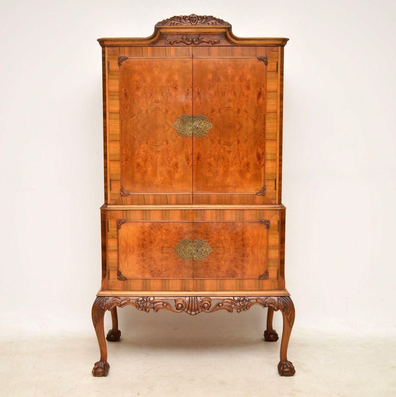 This antique Queen Anne style walnut cocktail drinks cabinet is very fine quality and in good original condition. It has a lovely mellow color and is beautifully carved on the top, plus around the legs, which have claw and ball feet. The four doors
