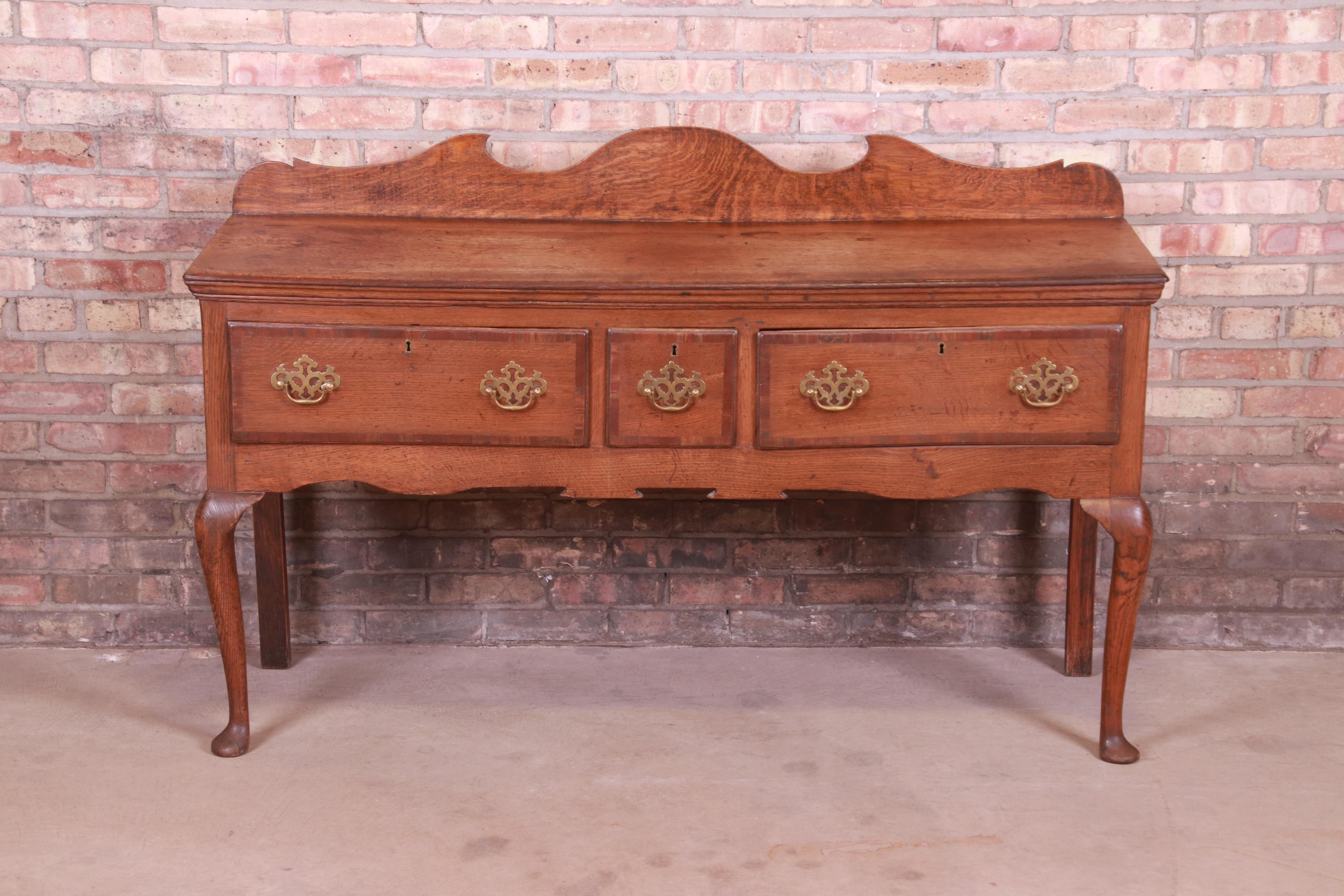 An exceptional Queen Anne sideboard, credenza, or console

England, circa 1790

Carved oak, with brass hardware.

Measures: 57.75