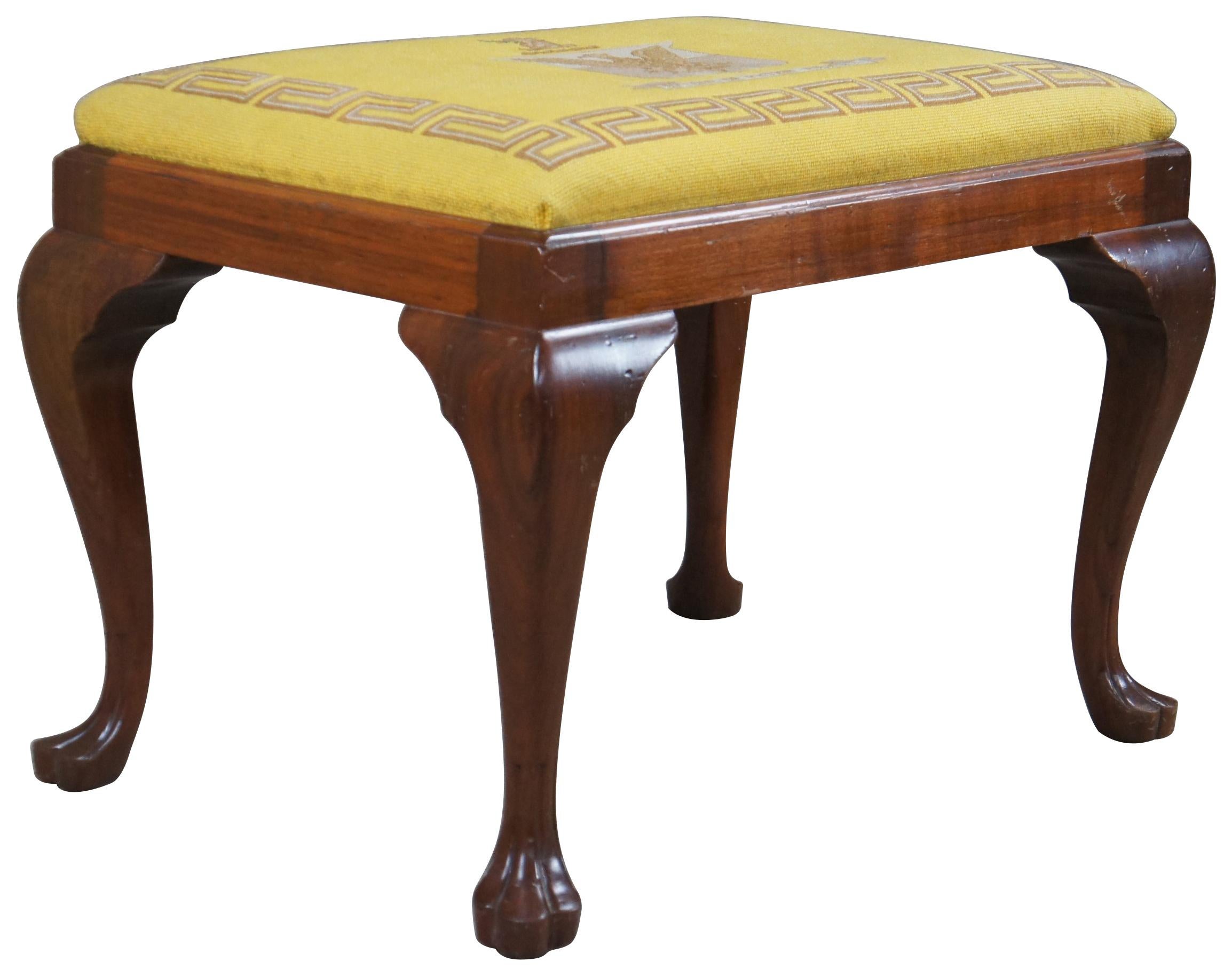 An impressive antique Queen Anne Stool or foyer bench, circa early 20th century. A rectangular form made from solid mahogany with cabriole legs leading to a trifid foot. The seat is upholstered in a needlepoint with a greek key surrounding a bird