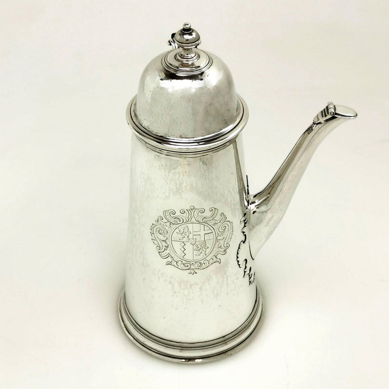 An impressive Queen Anne Silver Coffee Pot. The Coffee Pot has an engraved armorial on the side, a spout with a hinged cover and a wooden handle.

Made in London in 1703 by George Lewis.

Approx. Weight - 752g / 24.1oz
Approx. Height -