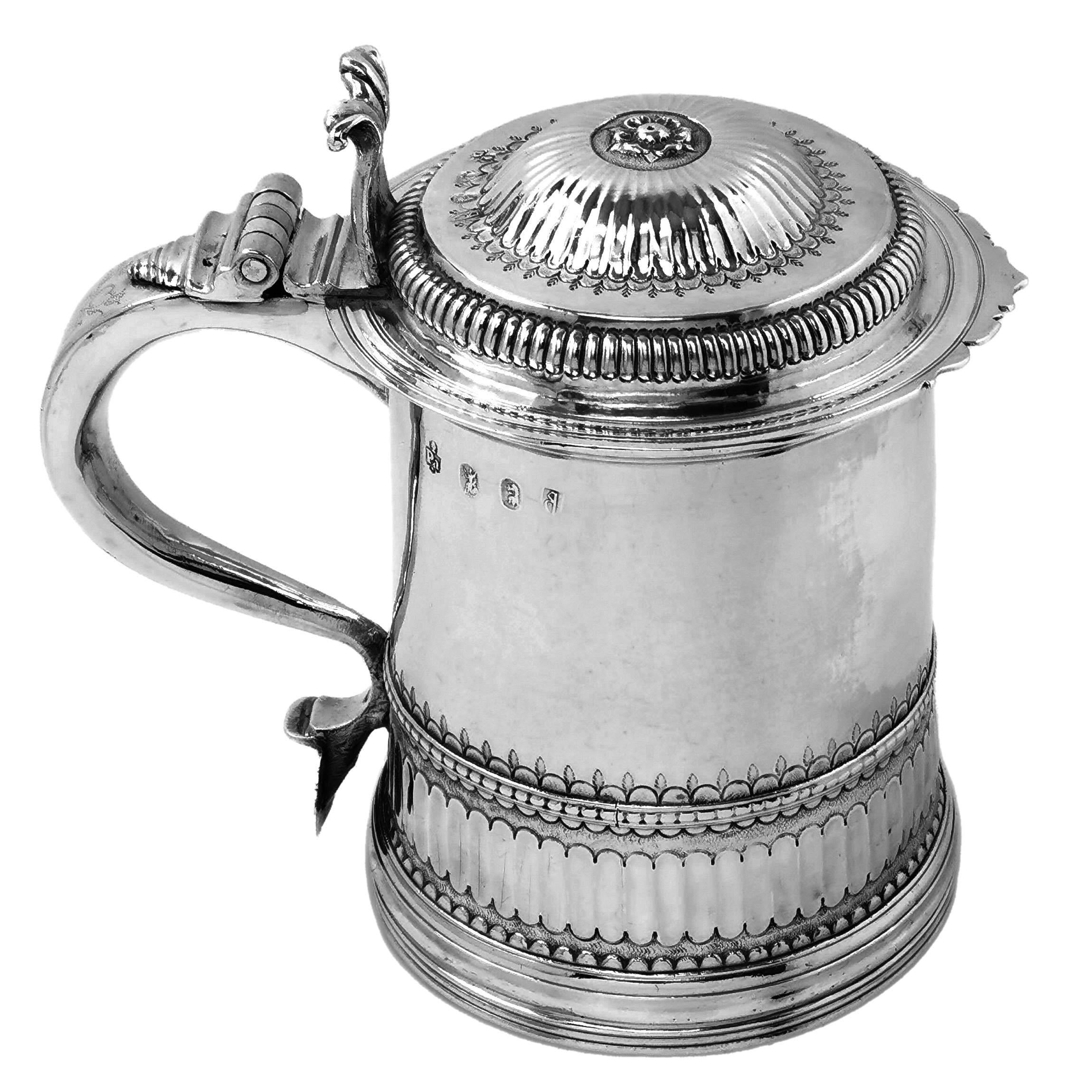 An impressive Antique Queen Anne Solid Silver Tankard with an elegant flued band around the body and a complementary fluted design on the domed lid. The chased design elements are enhanced by subtle engraved elements. The Tankard has a substantial