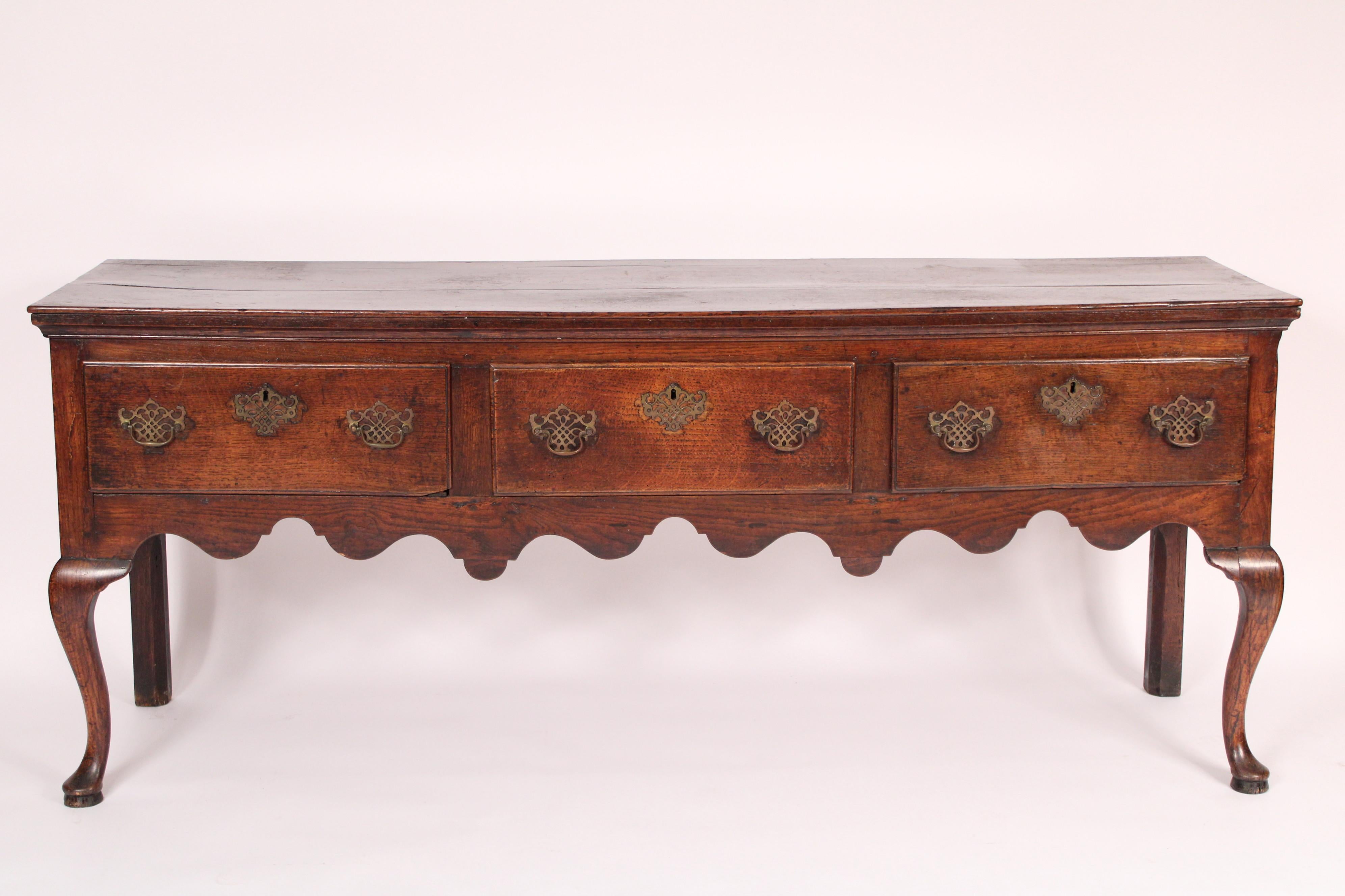 Antique Queen Anne style oak sideboard, 18th century. With a rectangular overhanging top,
3 frieze drawers, a scalloped apron, resting on cabriole legs ending in pad feet