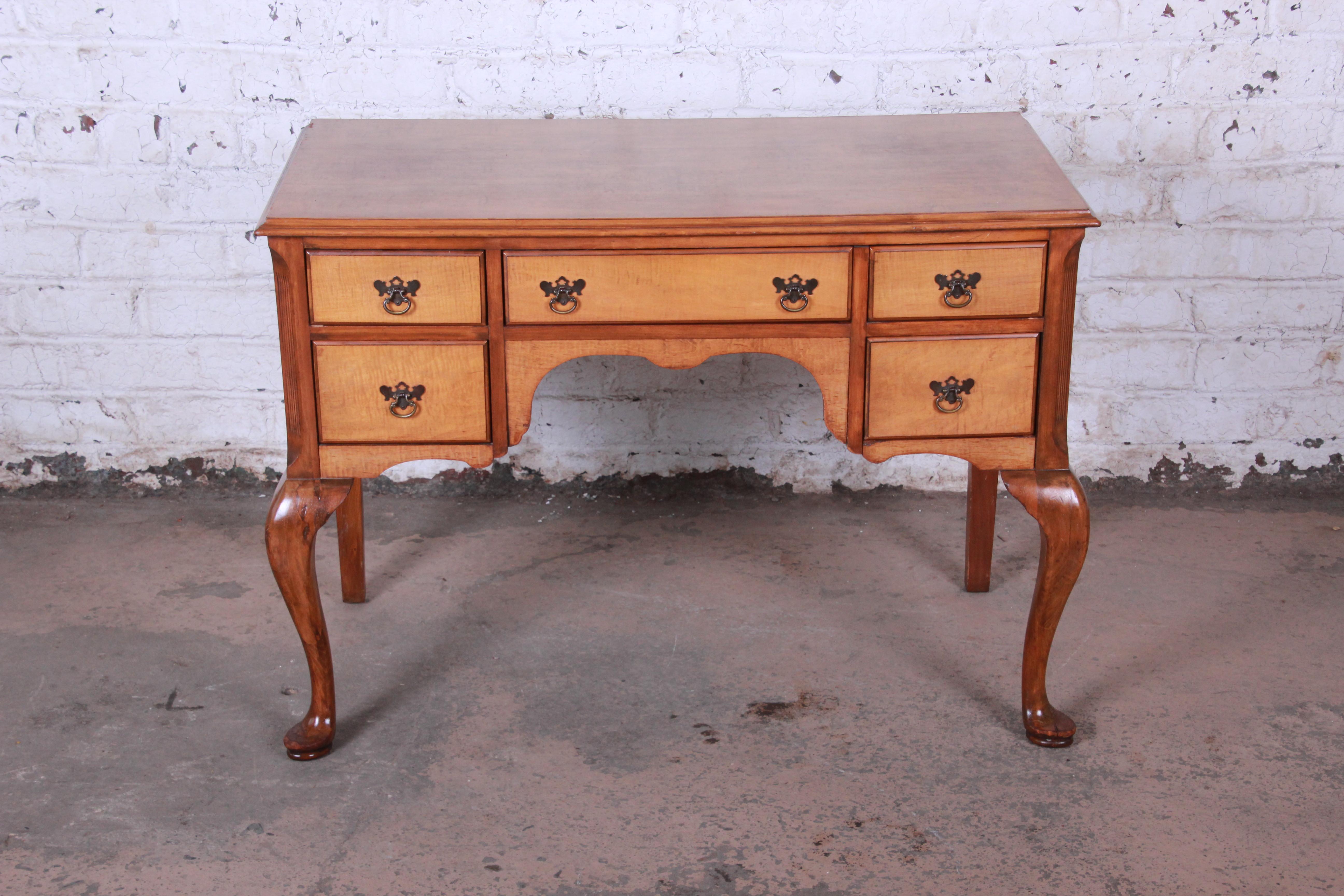 A beautiful antique Queen Anne style writing desk. The desk features gorgeous tiger maple wood grain and a nice traditional style. It offers good storage, with five dovetailed drawers. The desk was made in the early 1900s by J.B. Van Sciver Co. of