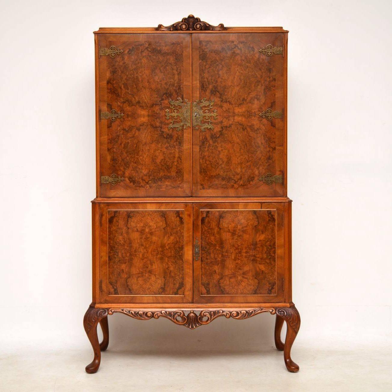 Antique Queen Anne style walnut cocktail drinks cabinet in good condition and dating from around the 1930s period. All the door panels are strongly patterned burr walnut, while the top doors have etched brass hinges and escutcheons. It’s carved on