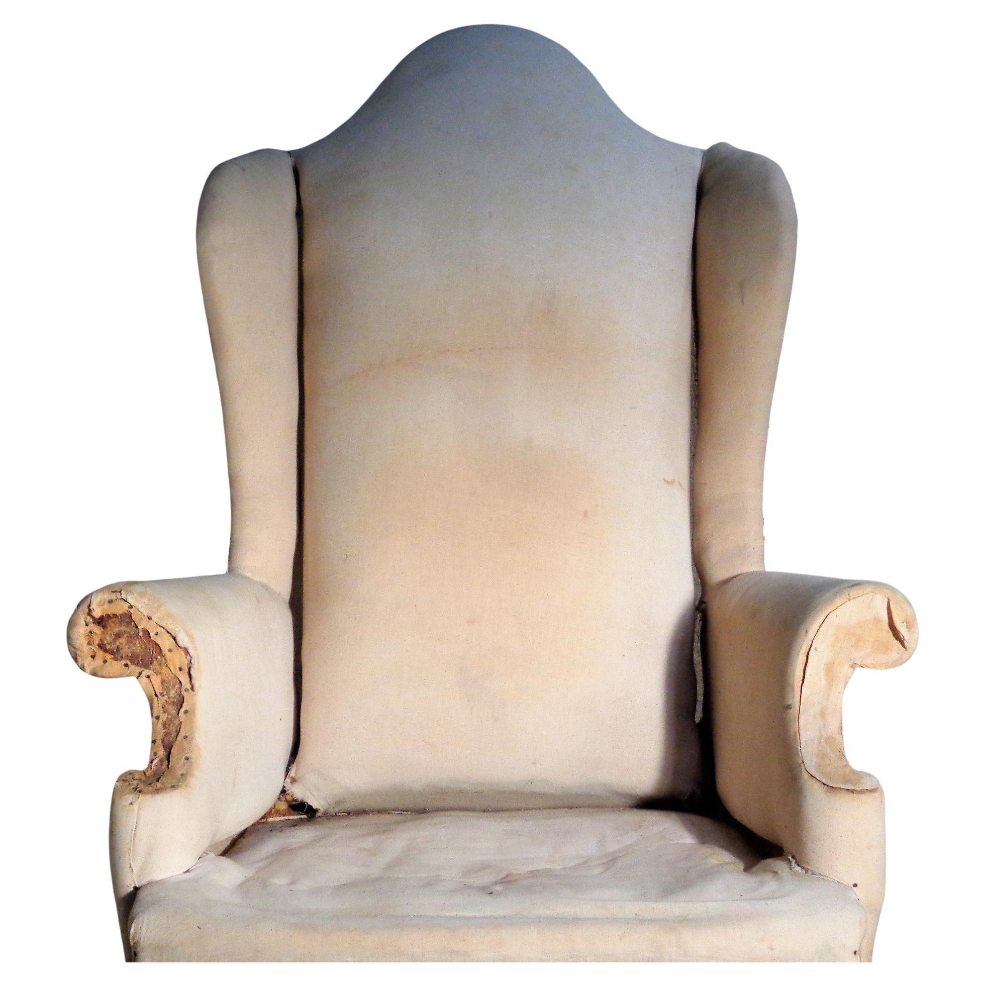 Antique Queen Anne style wing chair with beautifully shaped high back / rolled arms / carved front legs / interior wood framework. Chair has been stripped down to original muslin as shown in pictures. Circa 1900. Measures 52 1/2