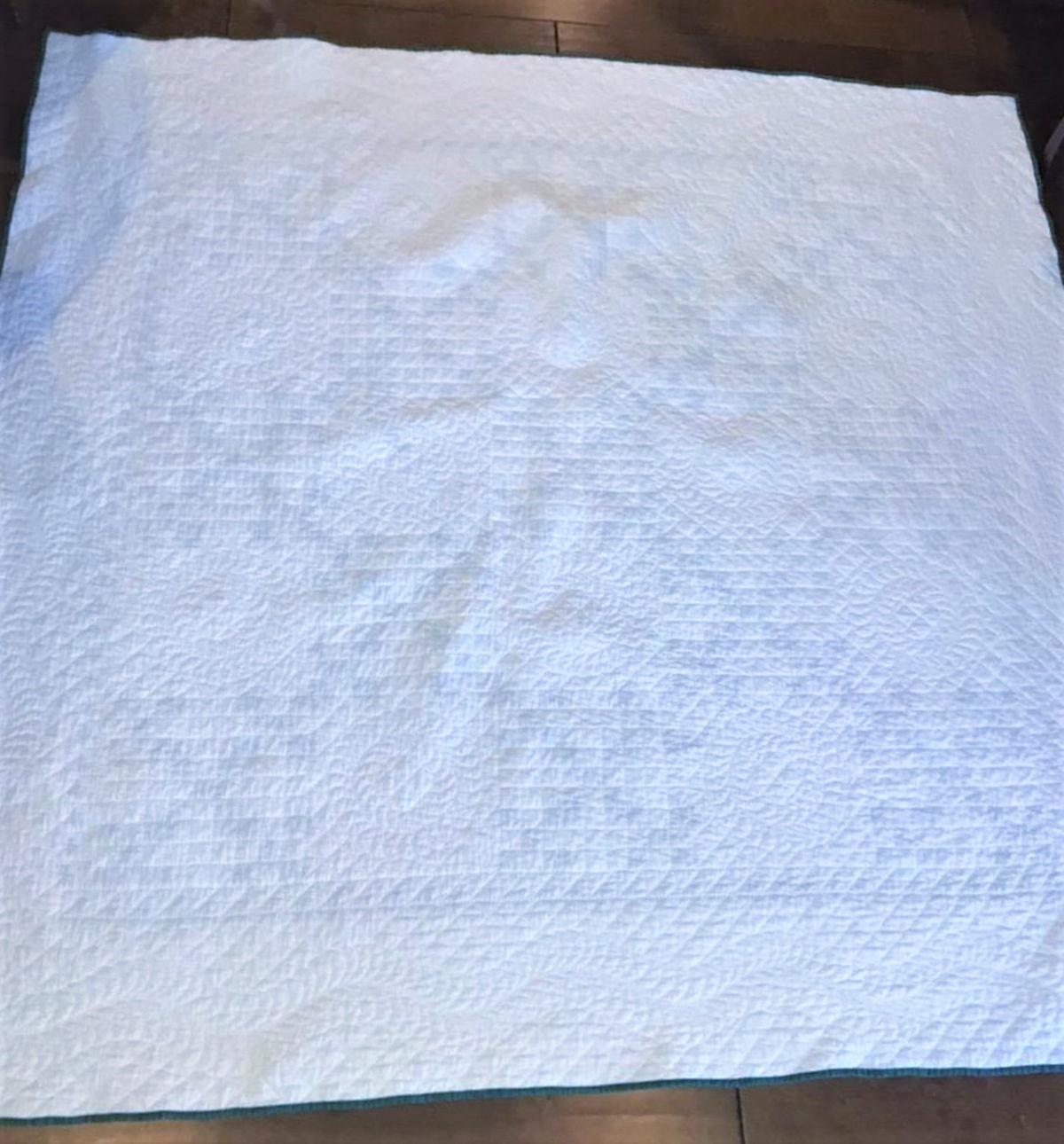 This fine heavily quilted green and white tiny postage stamp chain quilt in in fine condition. It also has a inner saw tooth border. The binding is also original to the quilt.