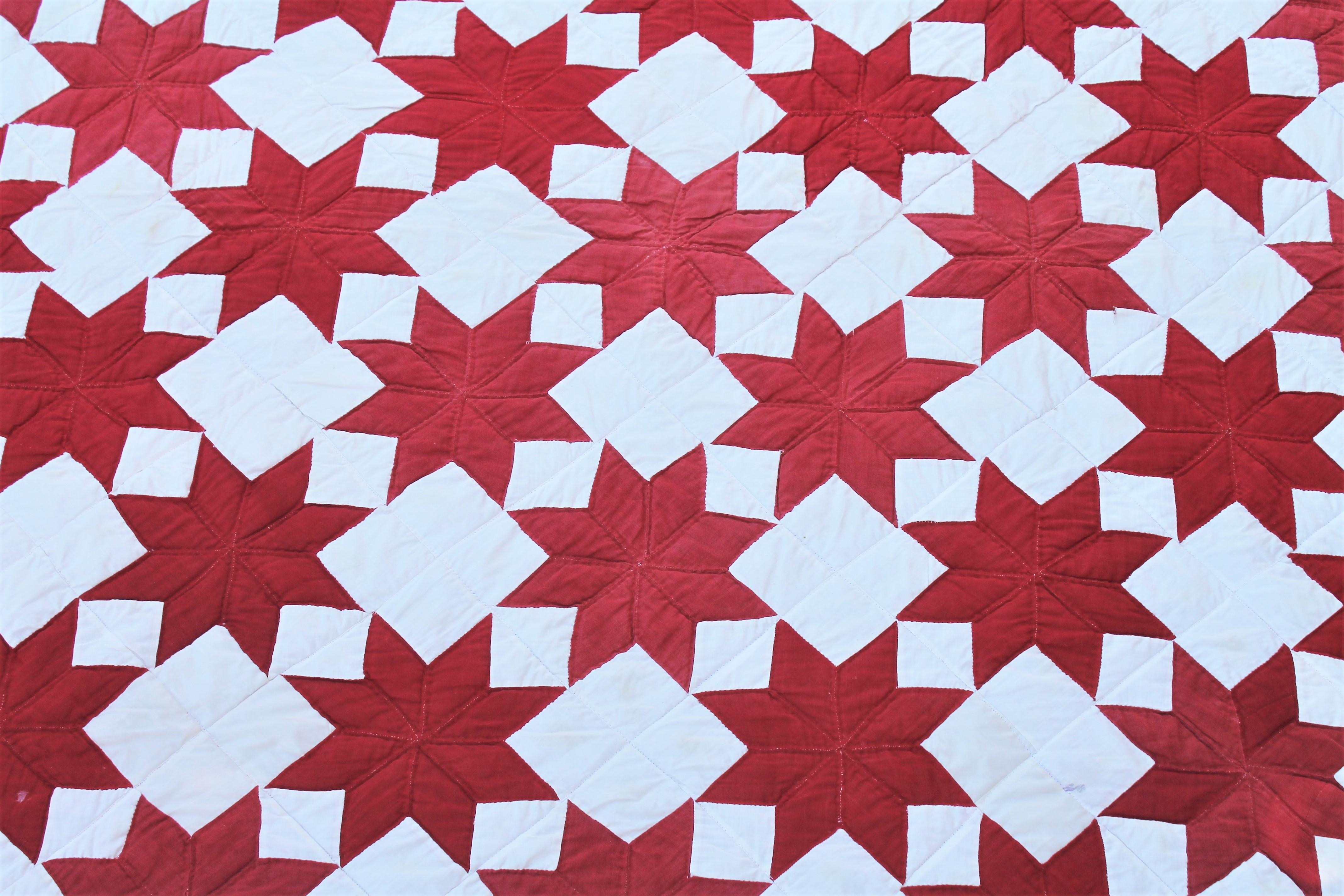 This fun and graphic red and white stars quilt with inner saw tooth border is in good condition. The binding is original to the quilt and the backing is in red fabric. The condition is good.