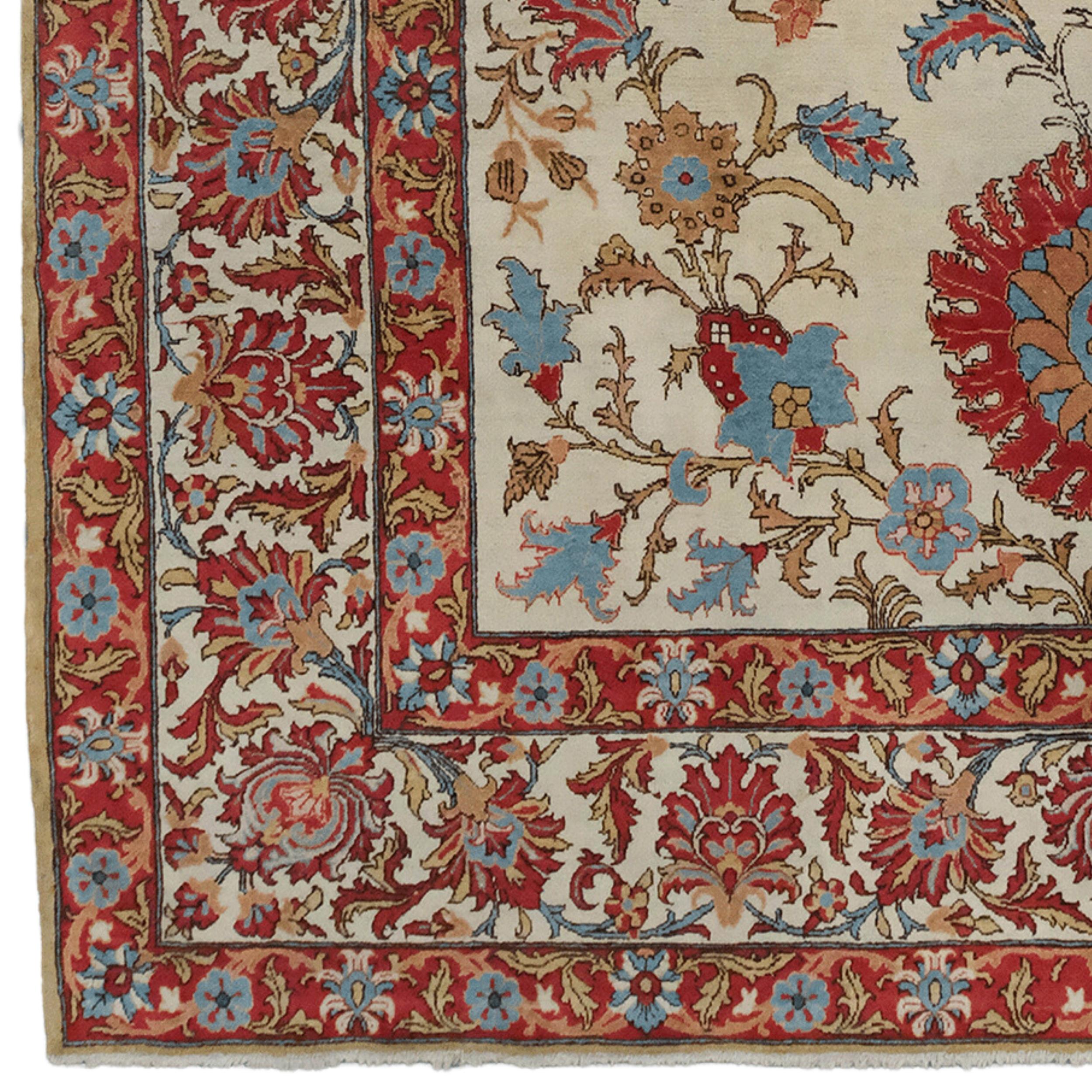 Ce tapis antique de Qum date du début du XXe siècle et a été tissé à la main à Qum, en Iran. Les motifs riches et complexes du tapis sont ornés de motifs iraniens traditionnels. Des motifs de fleurs et de feuilles dans des tons rouges, bleus et