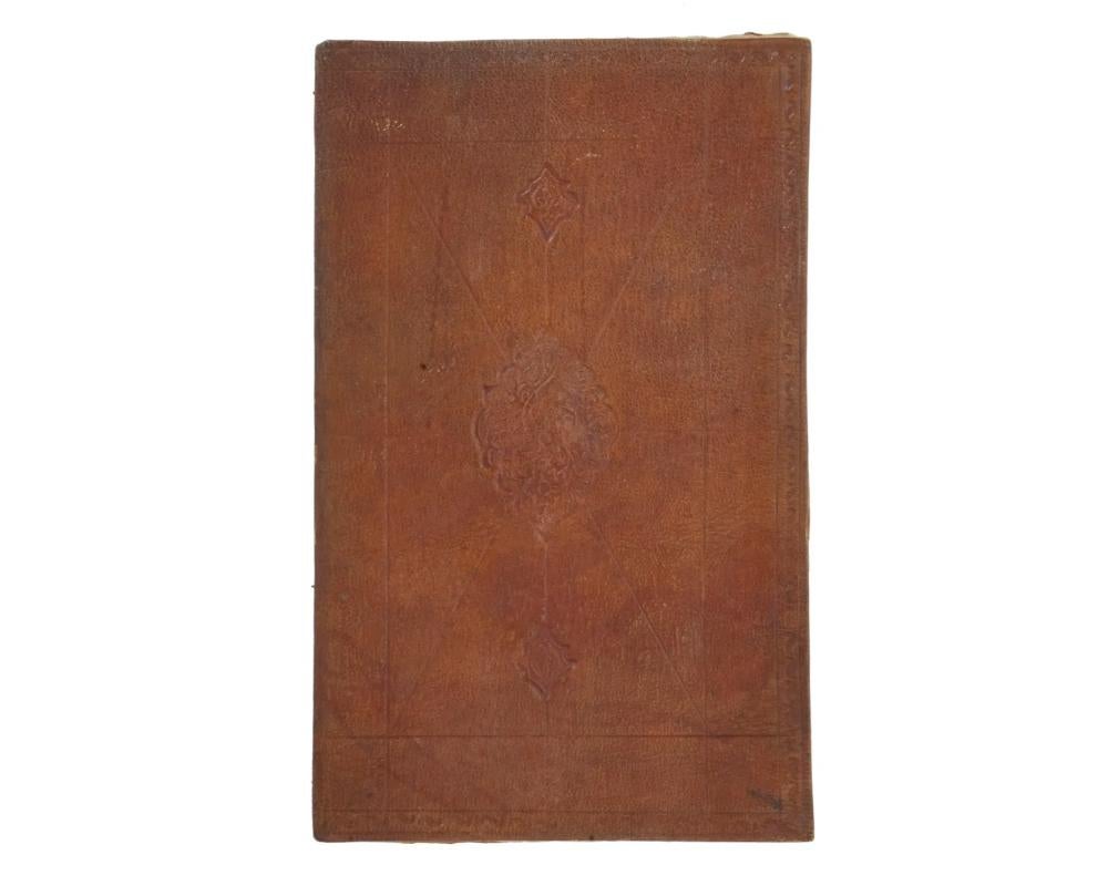 An antique Quran book with manuscripts. The hardcover of the book is adorned with embossed traditional ornaments. Circa mid to late 19th century. The Quran is the holy book of Muslims, written in Arabic. Antique Arabic Islamic Religious Books,