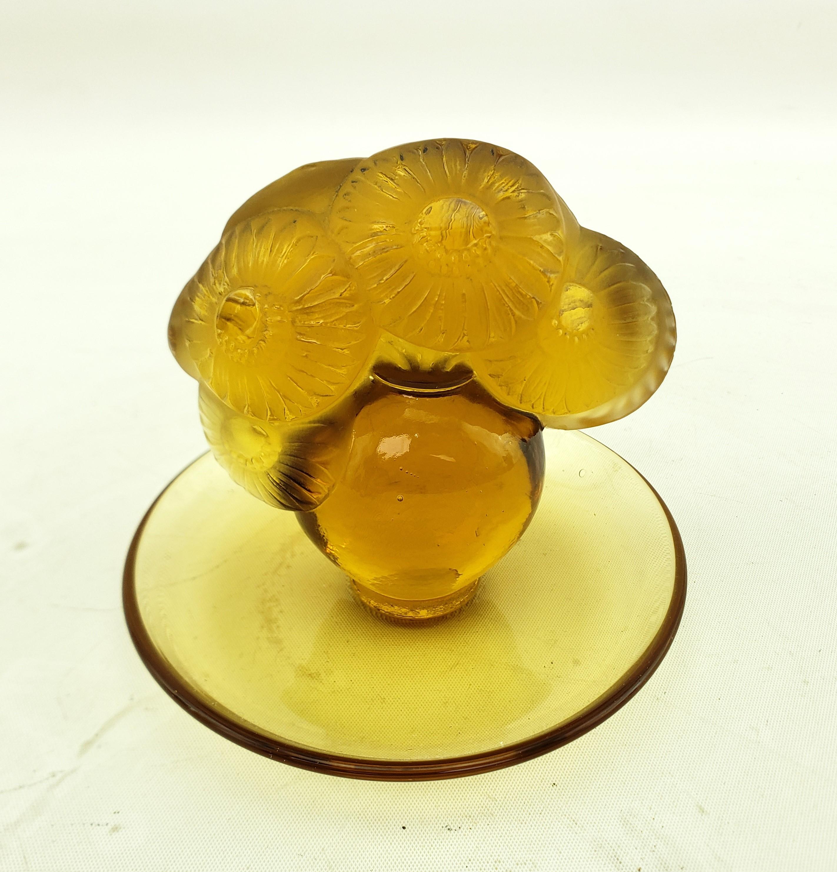 This antique pin dish was made by the renowned R. Lalique glass house of France and dates to approximately 1920 and done in the period Art Deco style. The dish or vide poche is composed of honey amber glass with raised handle composed of a figural