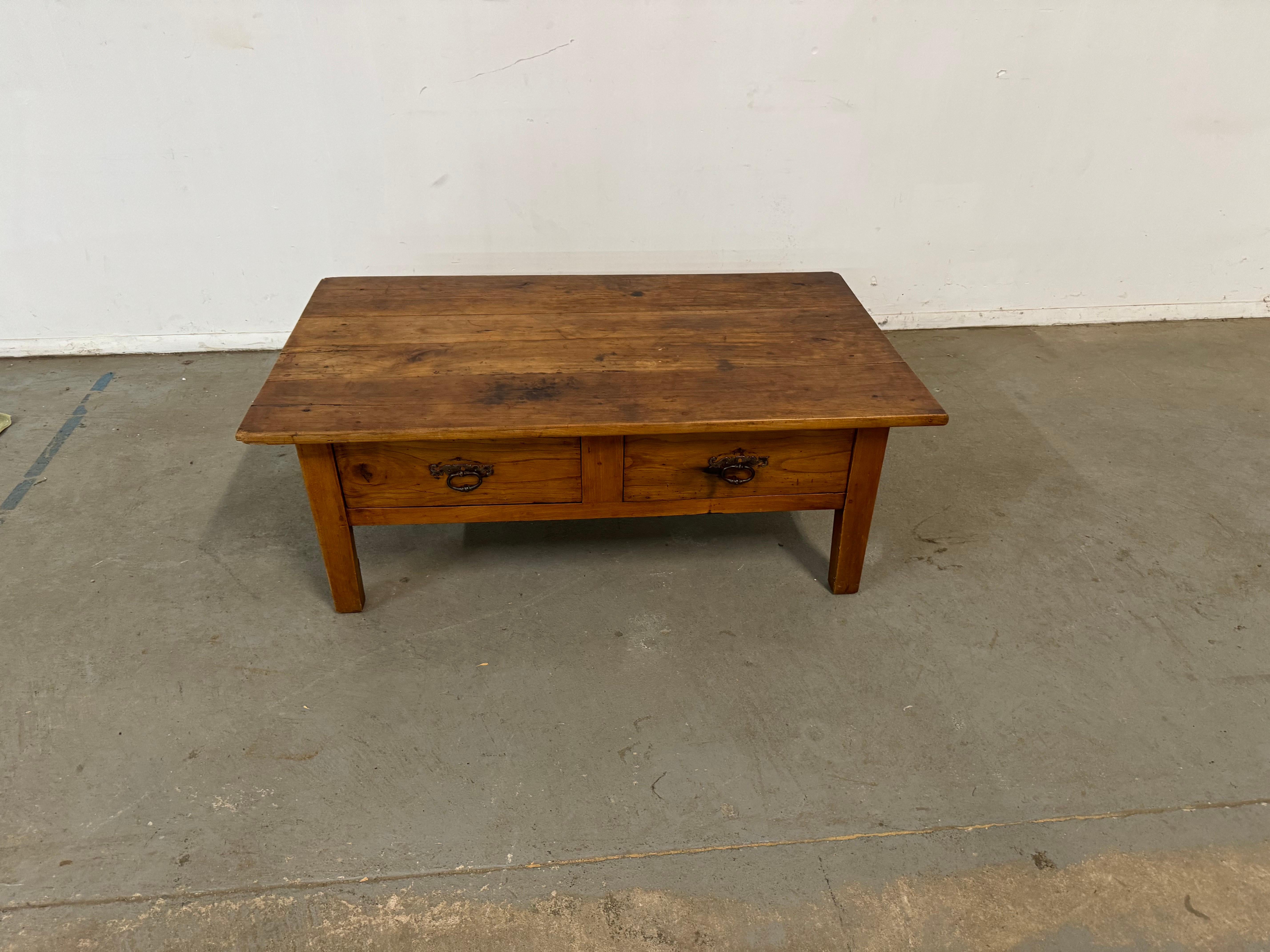Offered is a vintage rustic coffee table. The table has a great look, featuring a board top and 2 drawers. This piece is highly functional and will compliment any space or design project, It is estimated to be made circa ealry 1900's. It is in good