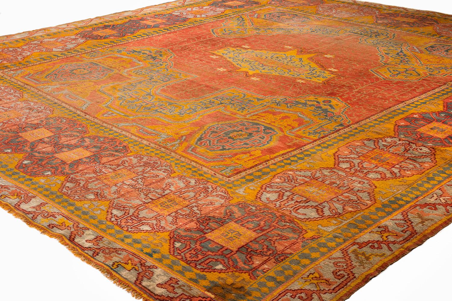 This exceptional 19th century Oushak carpet from western Turkey is a striking example of timeless elegance and bold design. The rug features an unusually oversized border, framing a field of cinnamon red that immediately draws the eye. At its