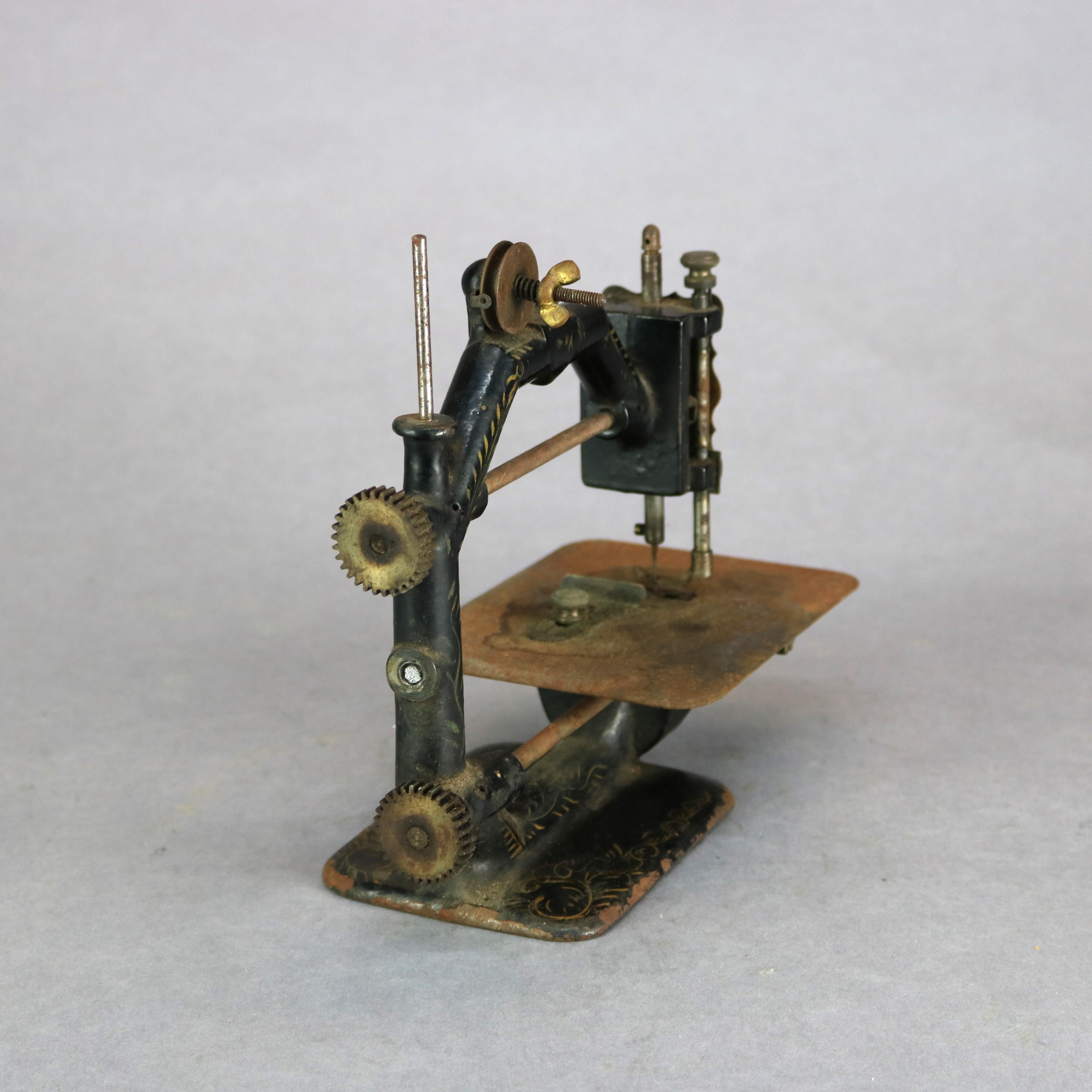 An antique early table top sewing machine offers rare form in cast construction with ebonized finish having gilt foliate decoration, c1850

Measures: 8.25