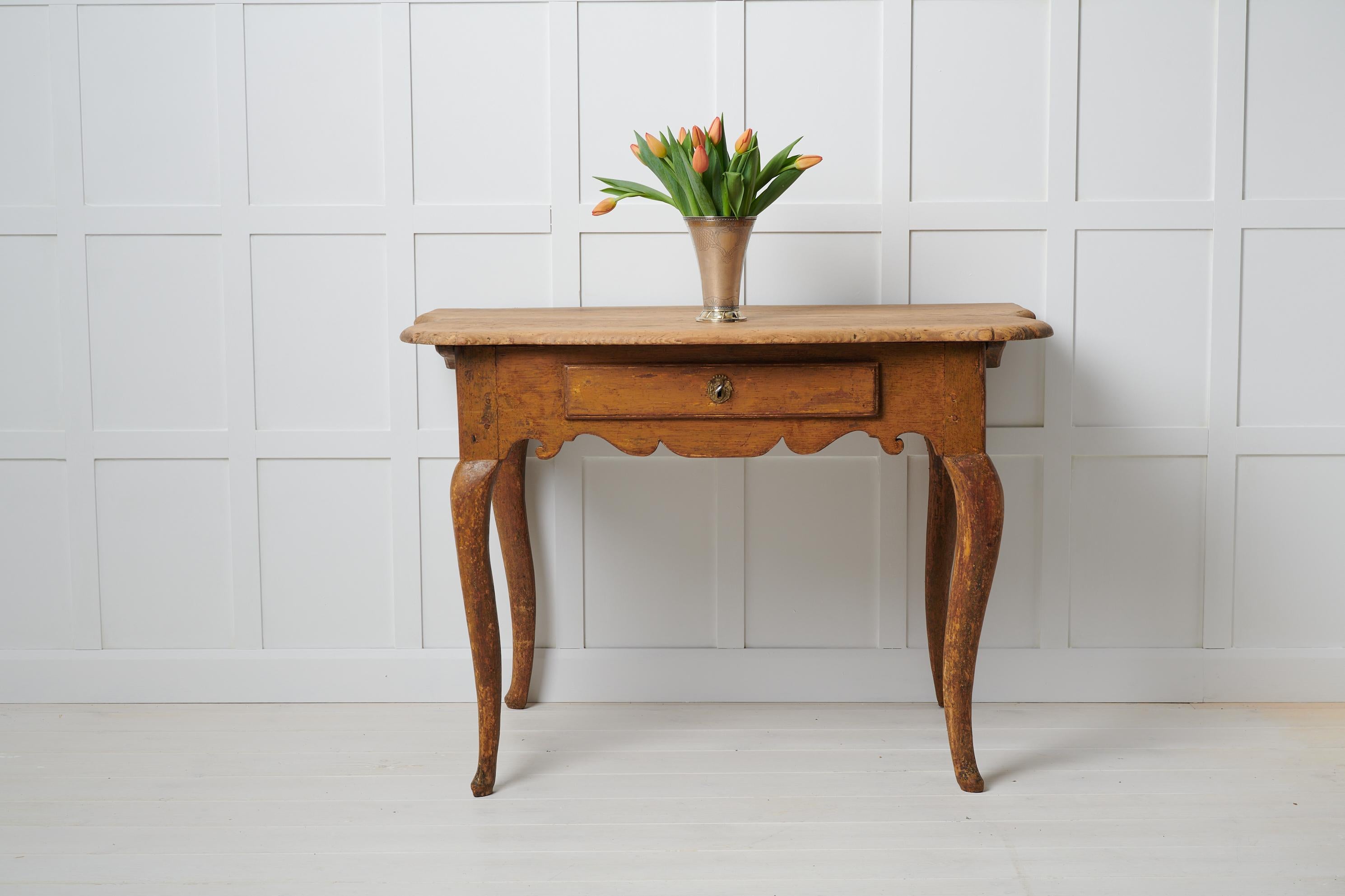 Rare antique baroque table from Sweden made during the mid to late 1700s, around 1770. The table is a wall table and is made in pine with a single drawer in the apron. The table top of the table has a decorative shape with curved sides and profiled