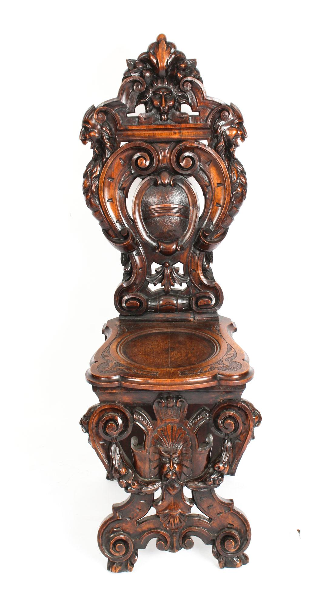 A pair of wonderful antique Italian Renaissance walnut Sgabello hall chairs, Circa 1820 in date.

They each feature a superbly carved coat of arms, a scrolling foliate decorated back, and a circular moulded seat. They are each raised on scrolling