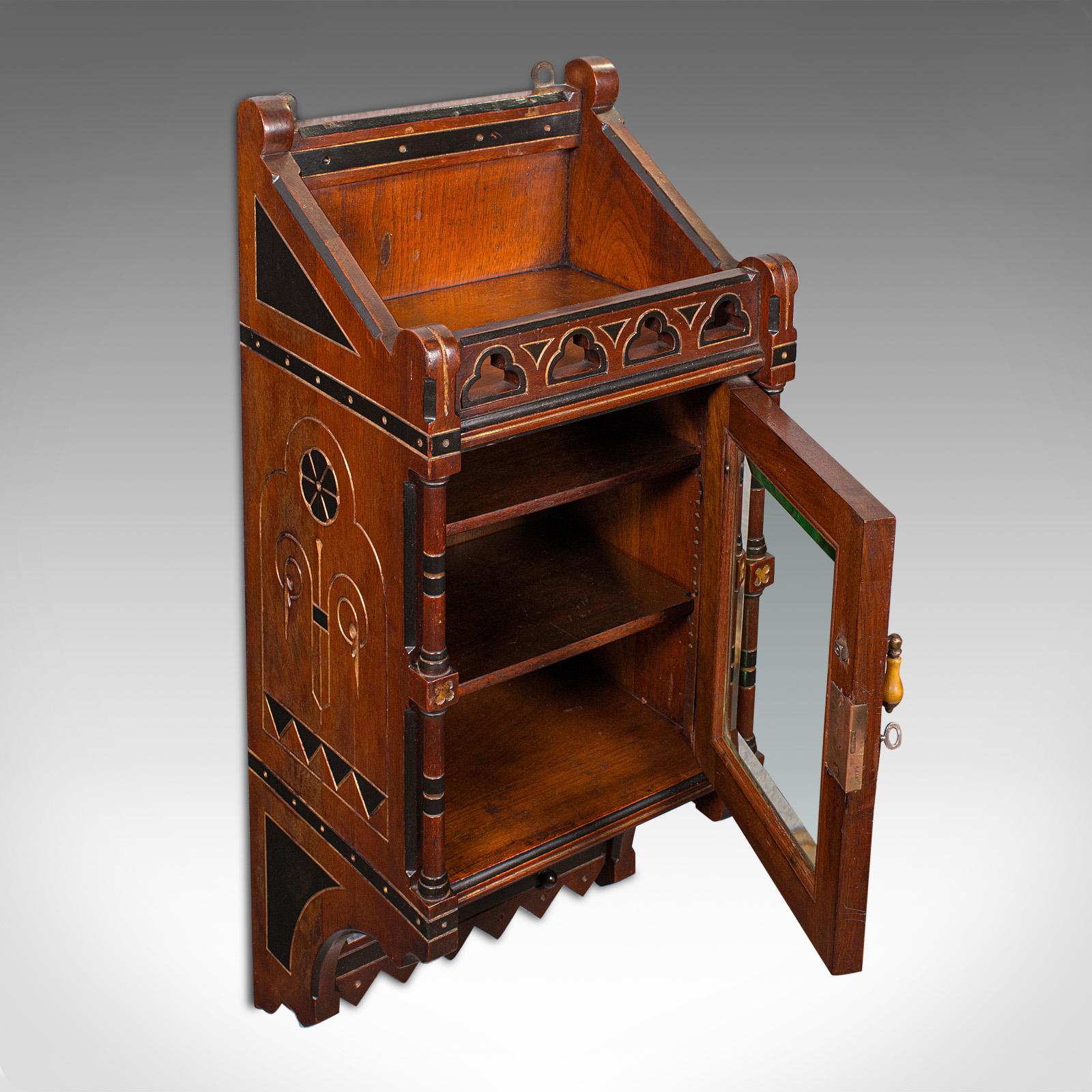 This is an antique reception hall cabinet. An English, mahogany glazed wall cupboard in Aesthetic Movement taste, dating to the late Victorian period, circa 1890. Exceptionally bold and beautifully crafted, this distinguished cabinet makes a refined