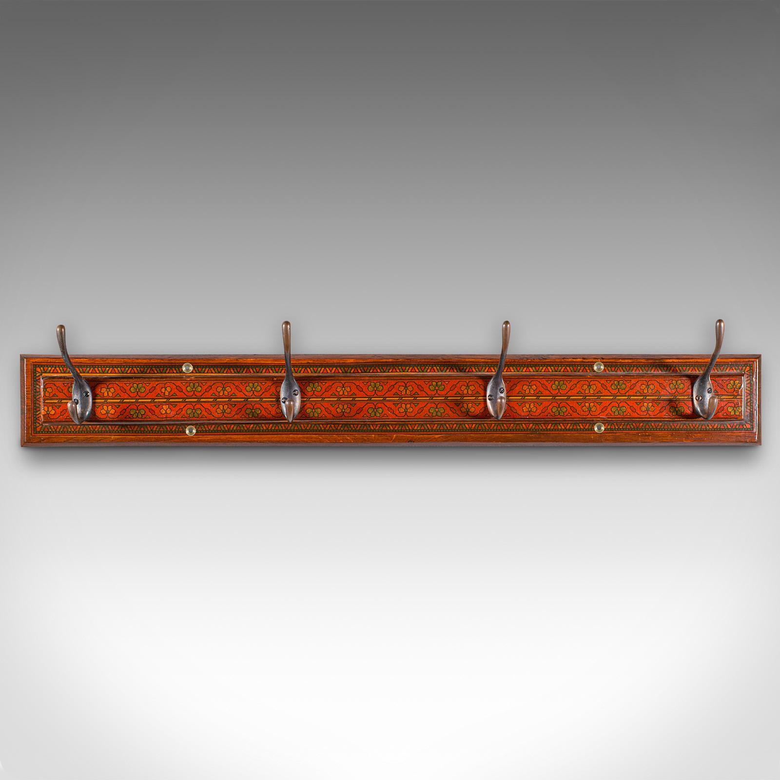 This is an antique reception wall rack. An English, hand painted oak hallway coat hook rail in Aesthetic period taste, dating to the late Victorian era, circa 1890.

Charmingly decorative set of hooks to brighten the entrance hall
Displays a