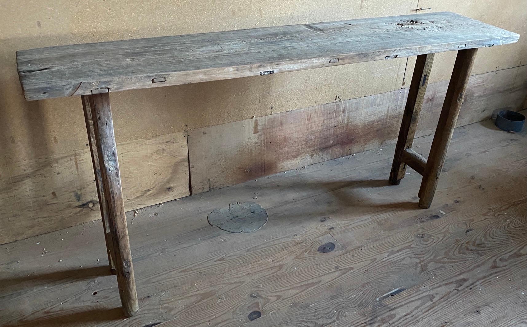 Styled a la Axel Vervoordt, this rustic console or sofa table is made from antique reclaimed elm wood giving it the character only naturally aged wood possess. 
Juxtaposed with modern angular lines, it features simple construction including