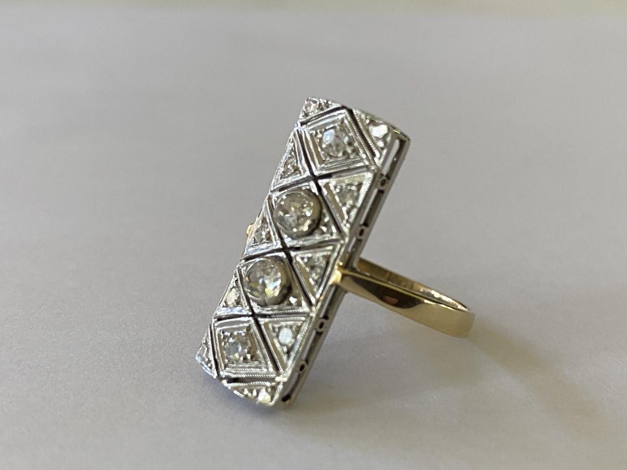 This vertical rectangular shaped dinner ring is designed around two Old Mine cut cushion-shaped diamonds each measuring 0.25 carats, accented with two smaller Old Mine cut diamonds measuring 0.10 carats each and further embellished with six single