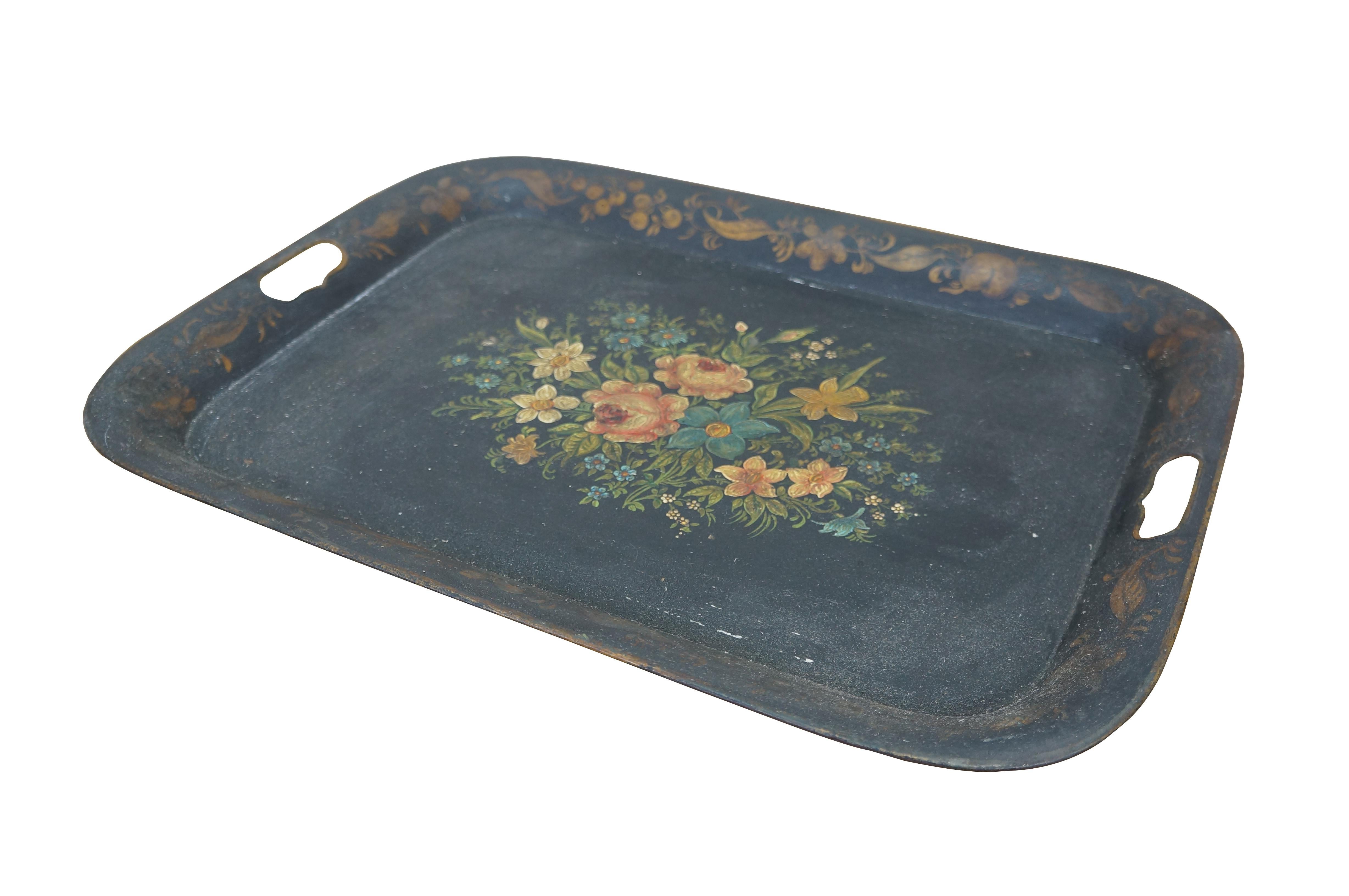 Plateau de service en métal noir antique. Forme rectangulaire arrondie avec poignées percées sur le bord. Bordure peinte avec des feuilles, des fleurs et des fruits dorés. Centre décoré d'un bouquet de fleurs variées roses, bleues, jaunes, blanches