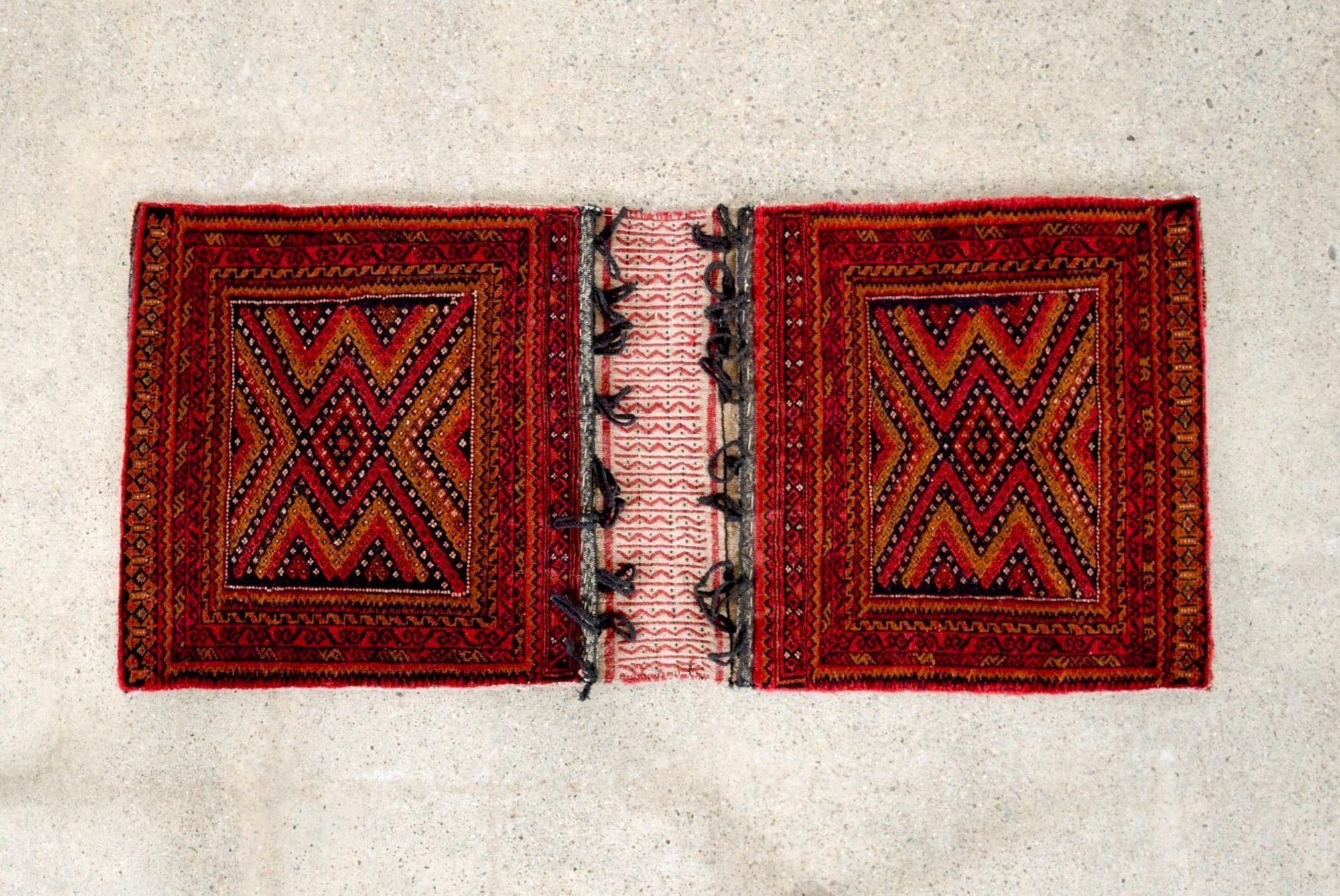 Dieser authentische Vintage-Satteltaschenteppich der Belutschen stammt aus einer Region in der Nähe des heutigen Afghanistan und Pakistan. Dieser kleine, fachmännisch handgefertigte Teppich ist durch flach gewebte Kelims mit Aufhängeschlaufen