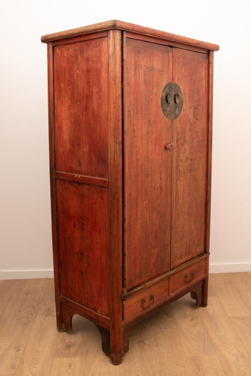 An antique Chinese wedding cabinet with two cupboard doors, upper and lower cupboard space and four drawers.