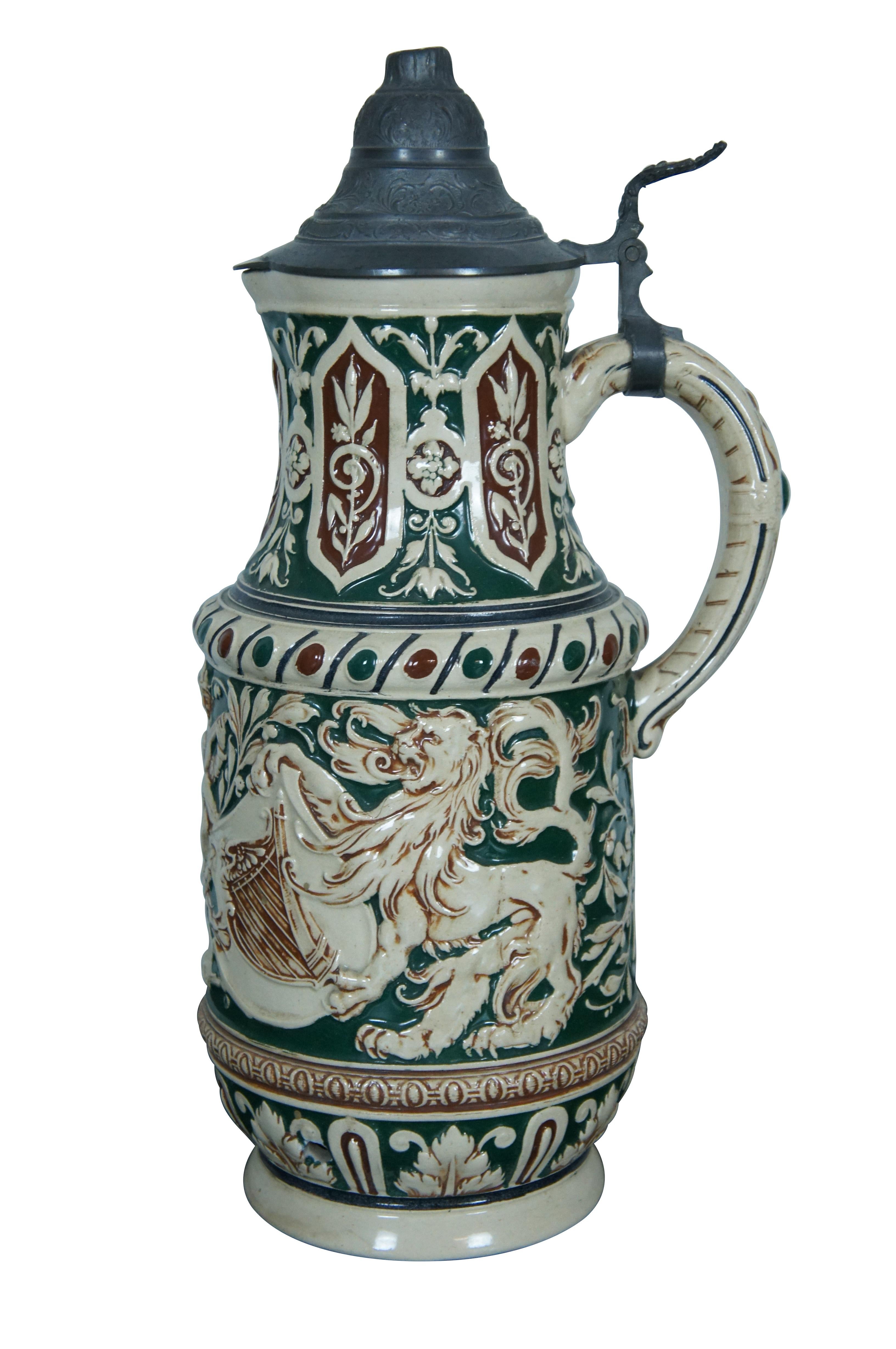 A beautiful old German stoneware stein. Features a red and green motif with Lions holding crests between a man with a Mandolin.  The text on the stein translates to Cheers! Drink according to the old German way.  Jude friends, happy circles.  The